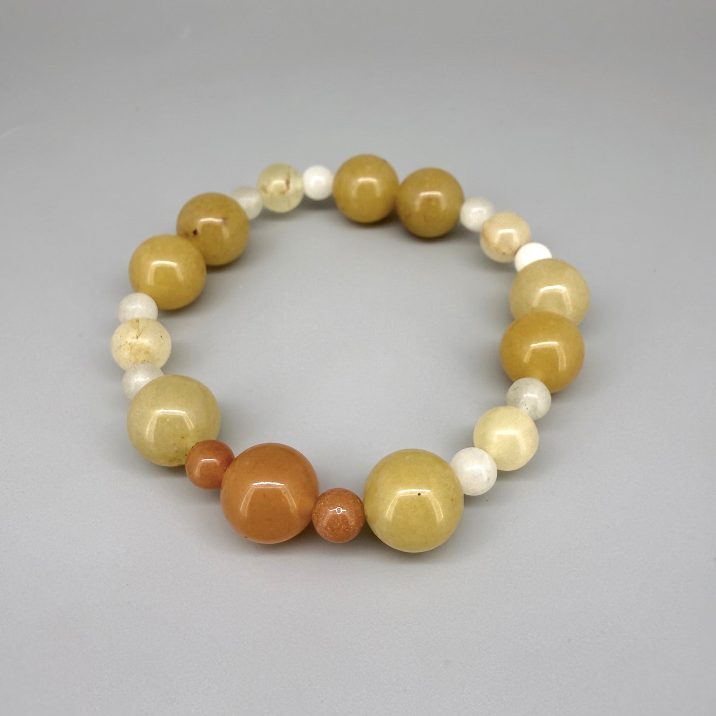 Jade beaded bracelet, 18cm, natural gemstone beads in yellow-cream, orange, and white tones on elastic stretch band.