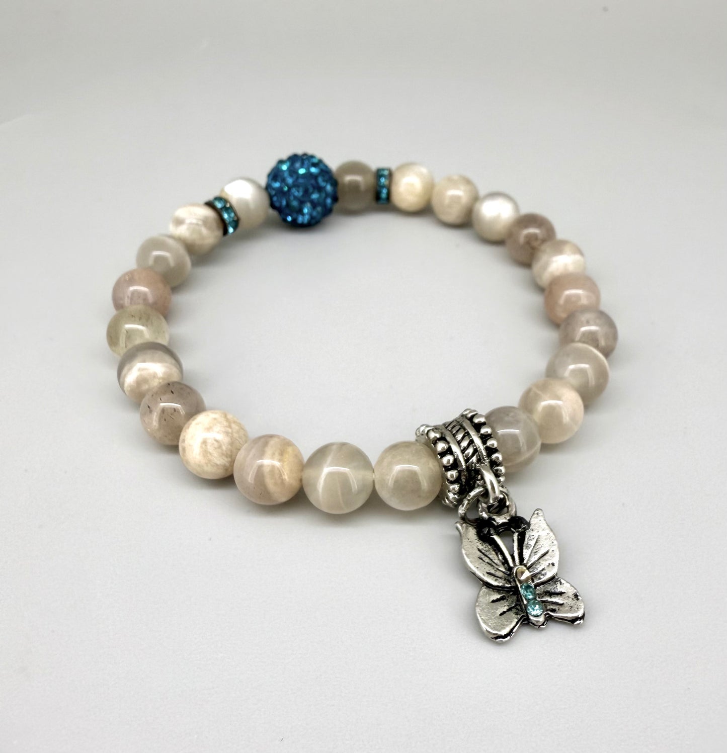 Moonstone beaded bracelet, 19cm, beige earthy gemstone beads with blue decorative bead and silver butterfly charm on elastic stretch band.