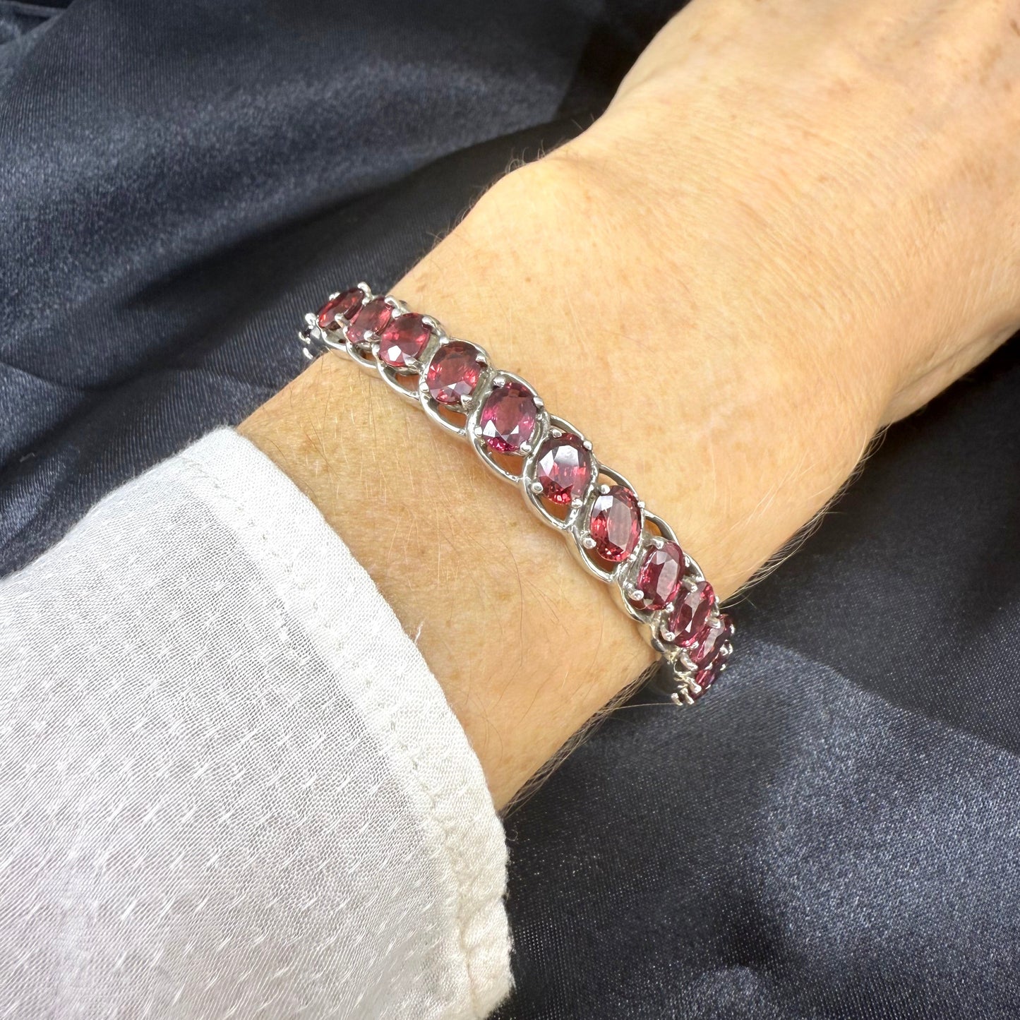 Rhodolite garnet bangle in sterling silver with white gold plating on neutral background