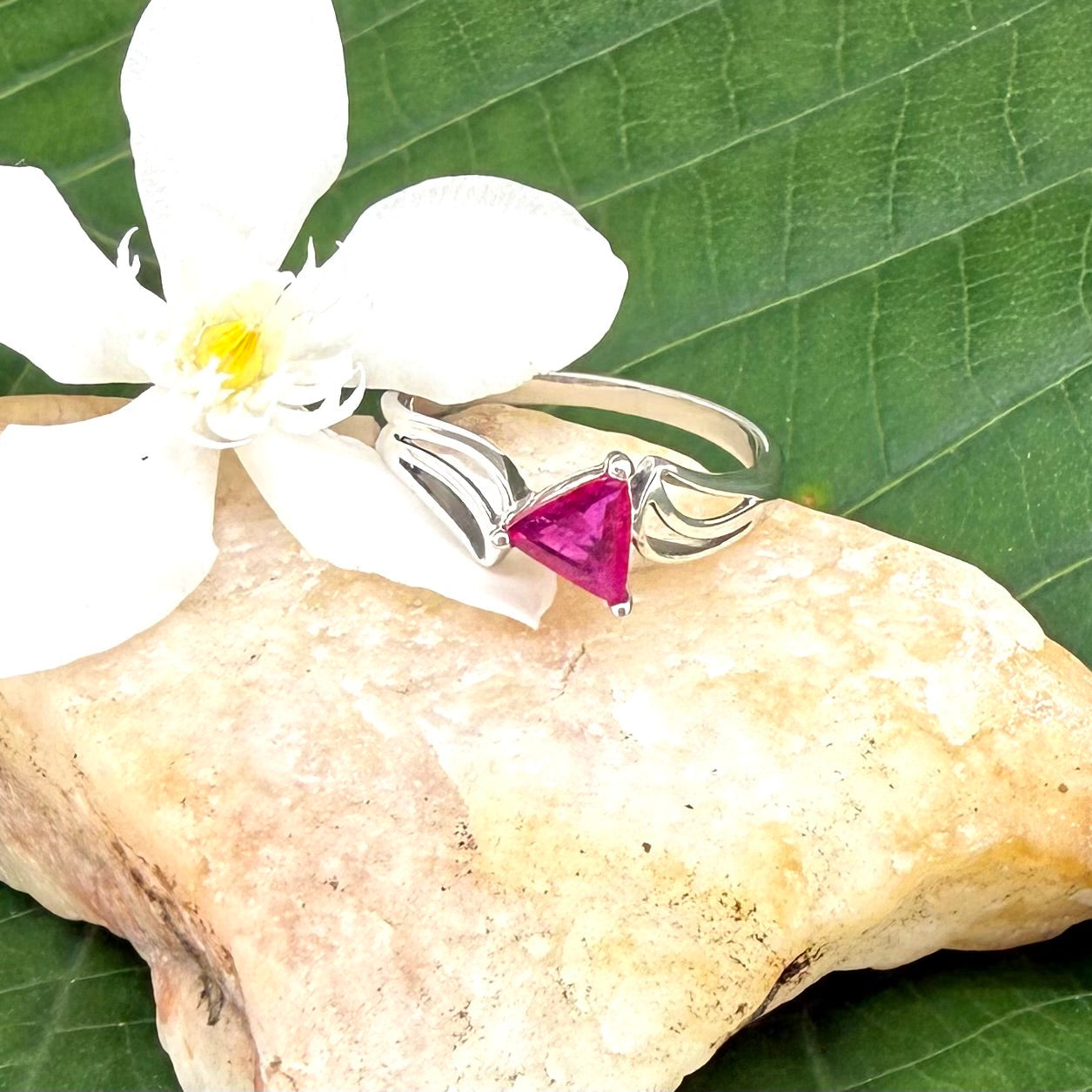 Ruby triangle-cut ring in white gold plated sterling silver, featuring a vivid red natural gemstone in a modern geometric solitaire design.