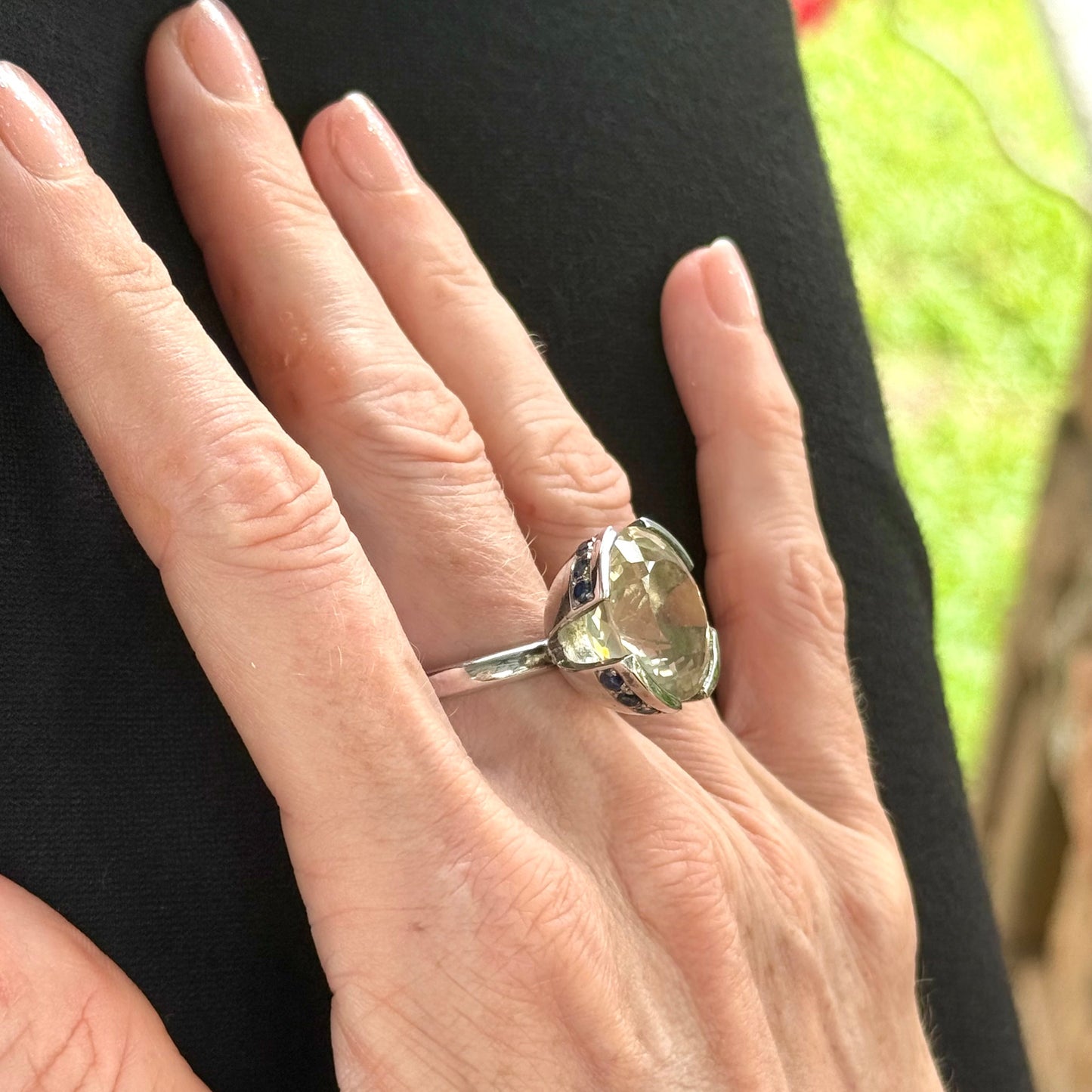 Lemon quartz and sapphire ring in white gold plated sterling silver, featuring a faceted yellow-green gemstone framed by deep blue sapphires, elegant and vibrant design.