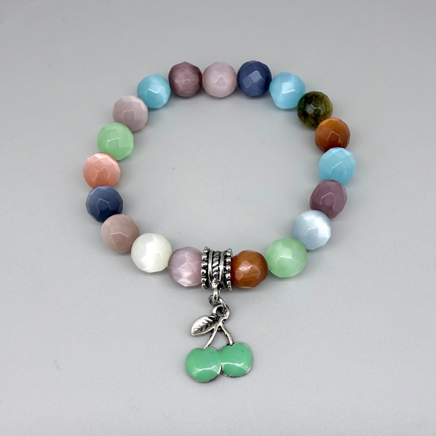 Pastel cat’s eye beaded bracelet, 19cm, multicolor shimmering beads with green cherry charm on elastic stretch band.