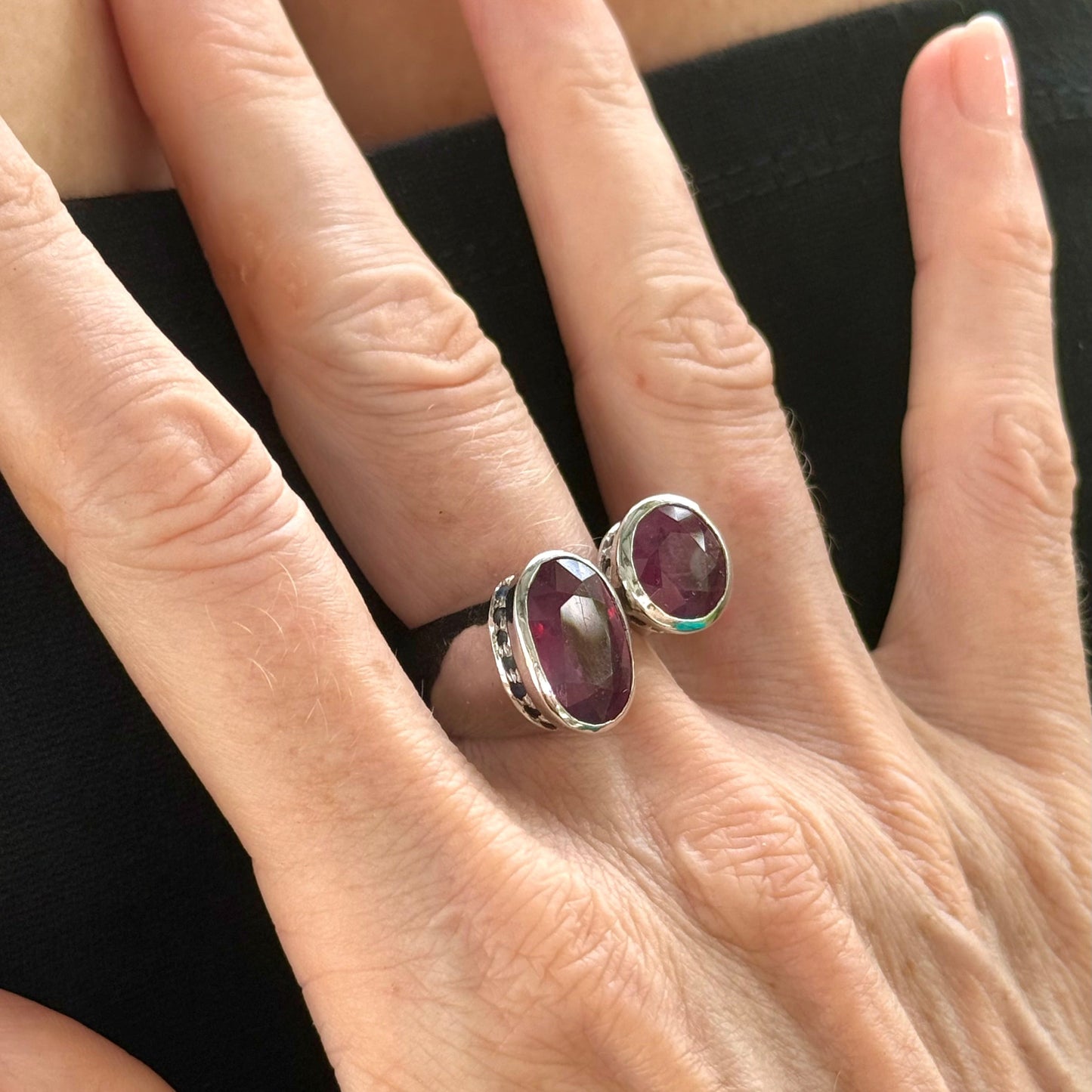 Ruby and sapphire bypass ring in white gold plated sterling silver, featuring two natural red rubies framed by blue sapphires in an open design, elegant and bold style.
