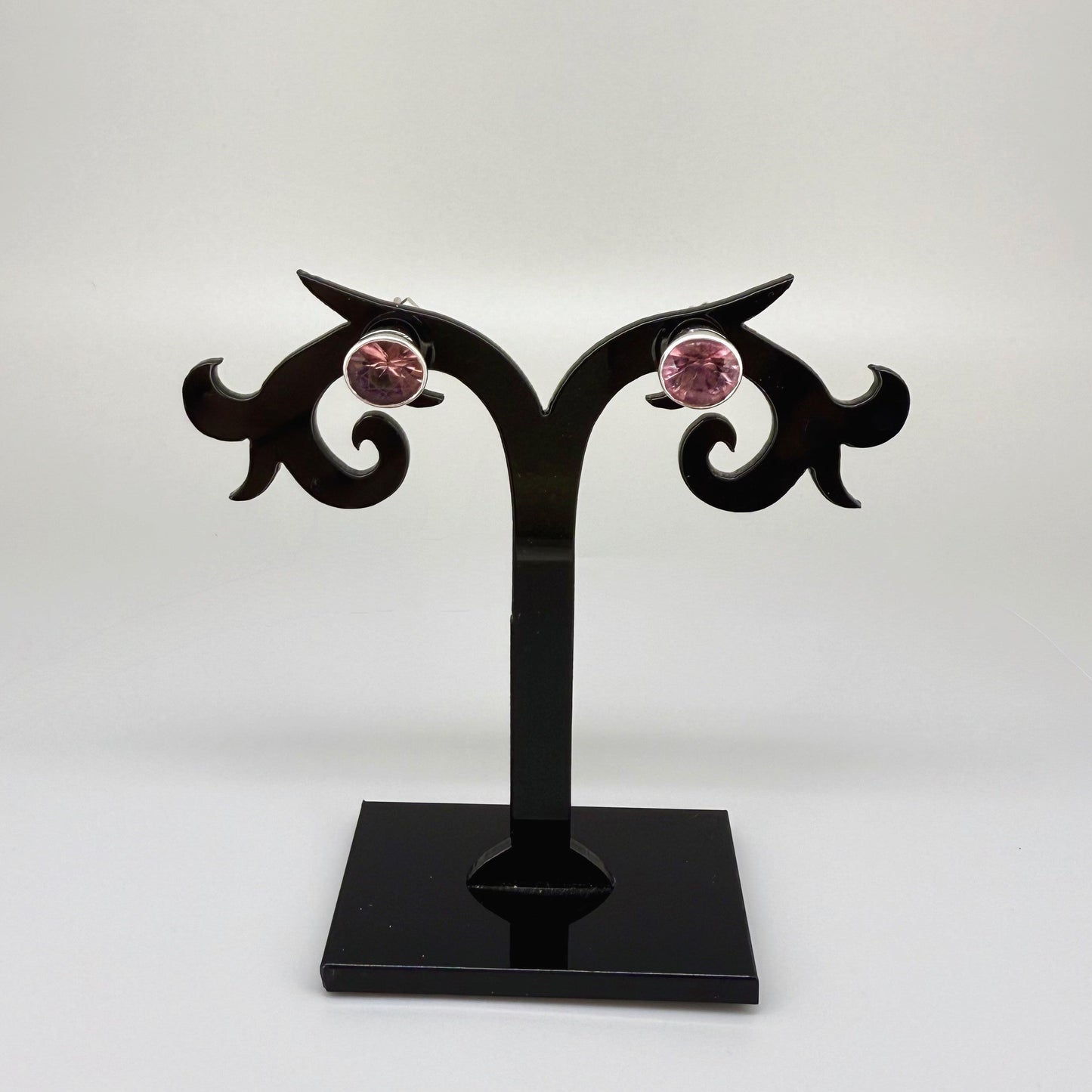 White gold plated sterling silver stud earrings featuring round-cut rhodolite garnets in a classic setting.