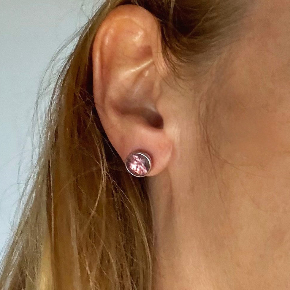 White gold plated sterling silver stud earrings featuring round-cut rhodolite garnets in a classic setting.