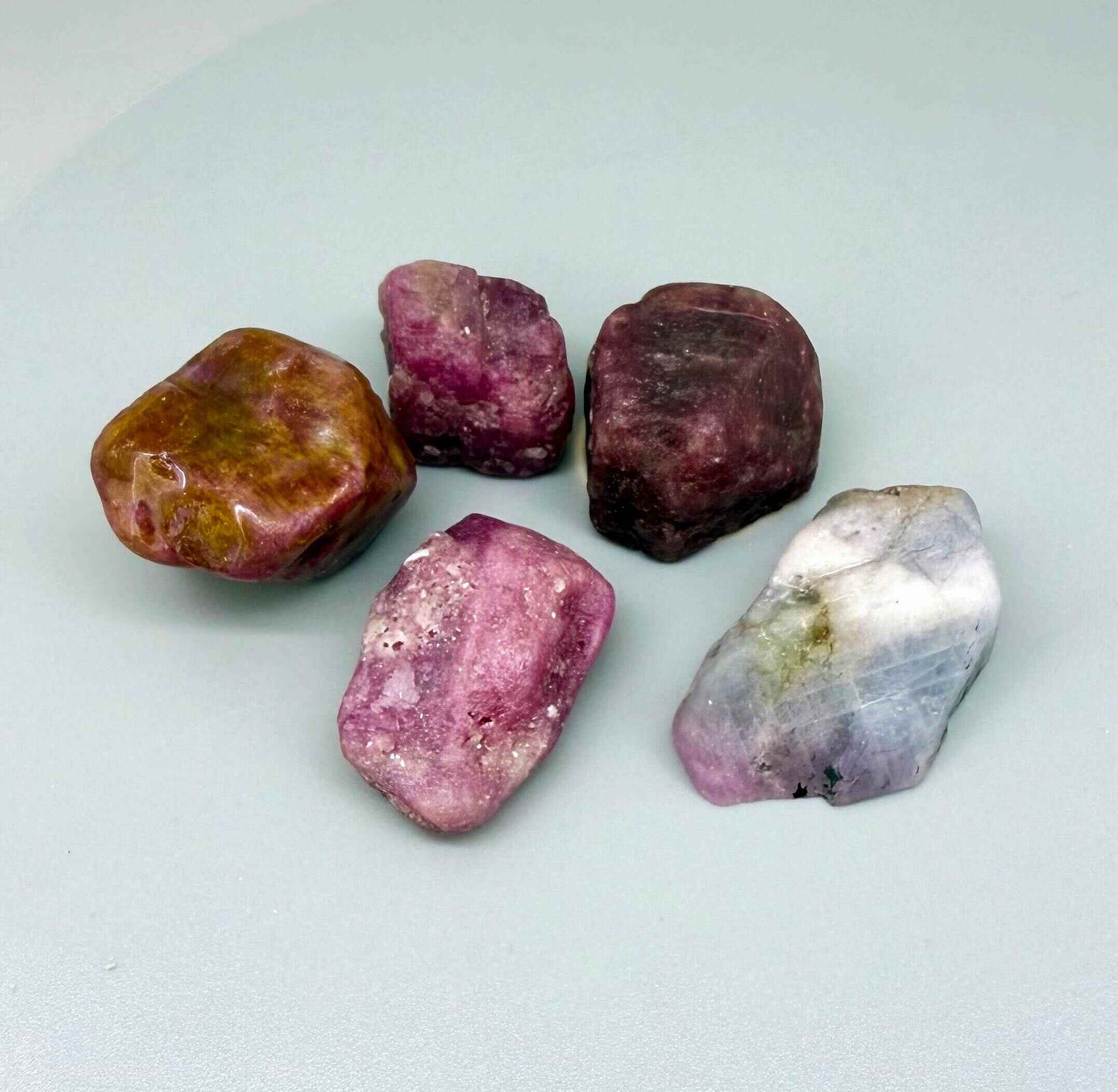 Natural ruby rough lot with pink to purplish-pink and raspberry tones, uncut corundum stones.