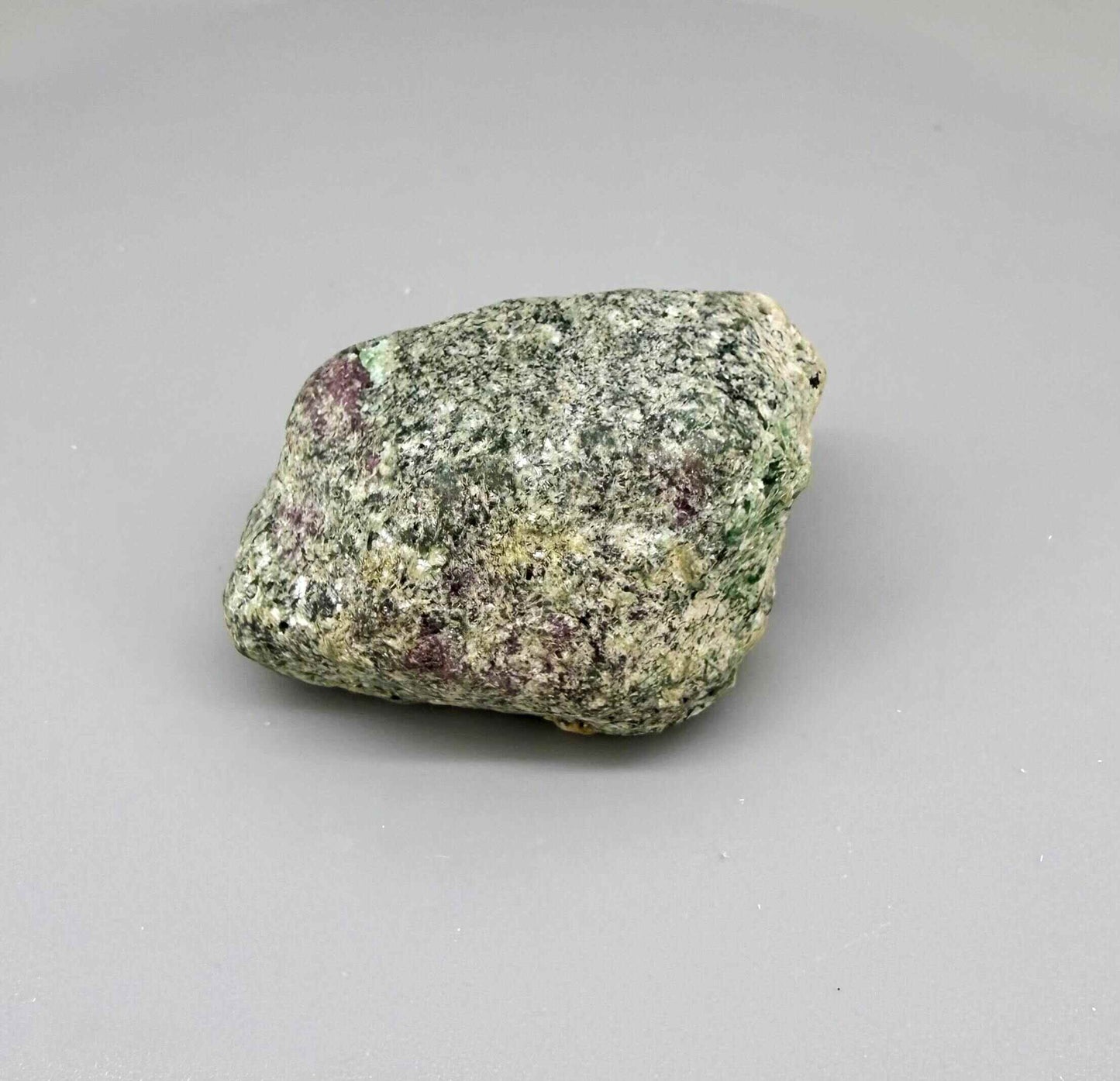 Natural ruby in matrix rough stone with grey-greenish host rock and vivid pink ruby core, uncut specimen.