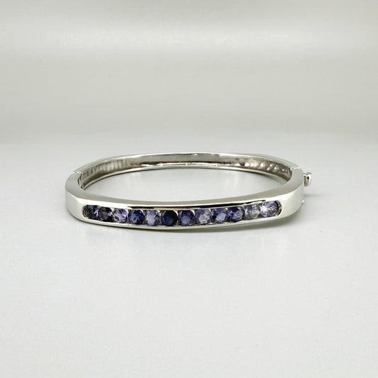 White gold plated sterling silver bangle with faceted natural iolite gemstones in violet-blue tones.