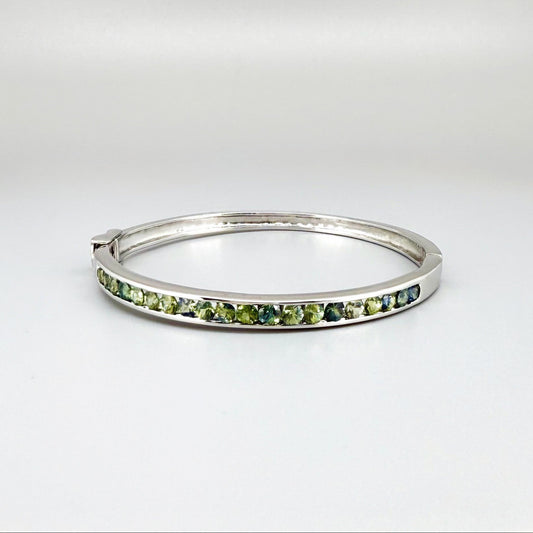 White gold plated silver bangle set with faceted natural green sapphires.