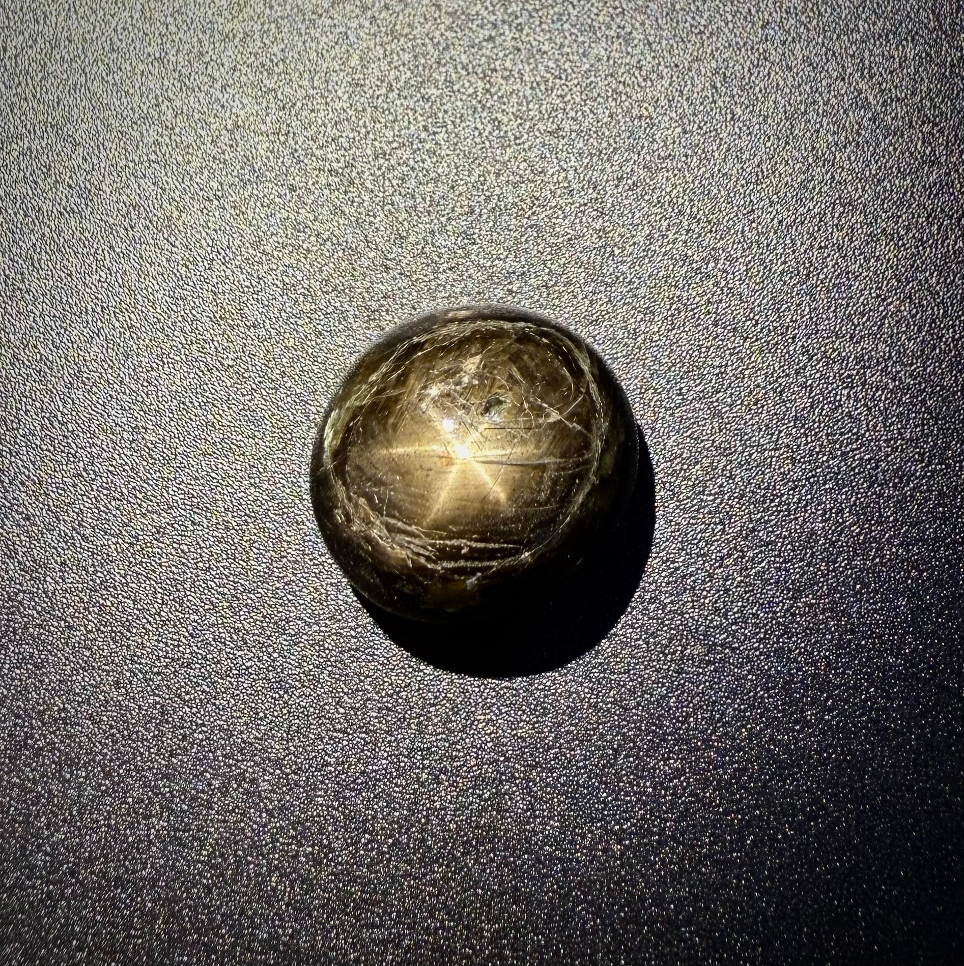 Golden-brown star sapphire cabochon, natural gemstone with visible asterism