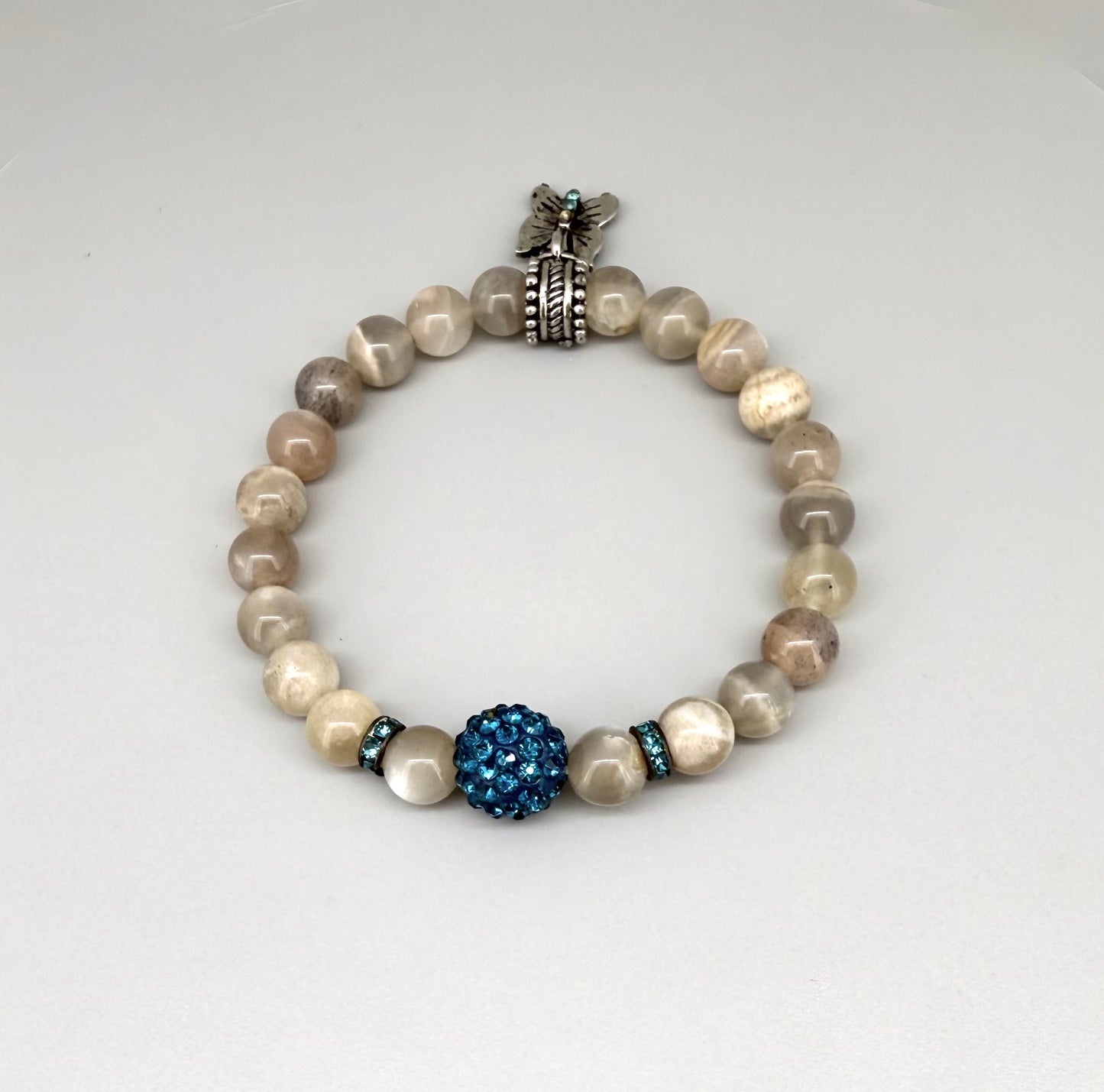 Moonstone beaded bracelet, 19cm, beige earthy gemstone beads with blue decorative bead and silver butterfly charm on elastic stretch band.