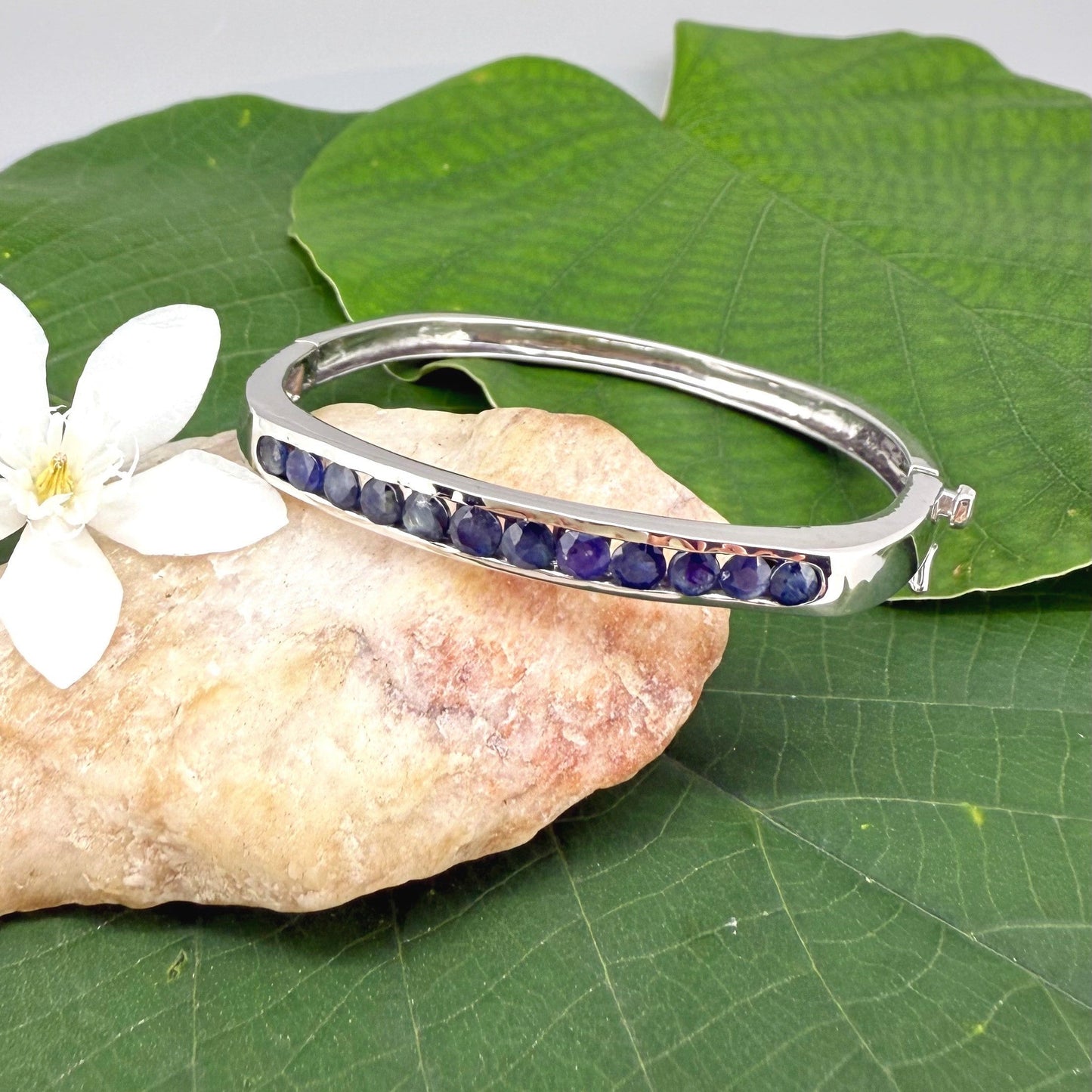White gold plated silver bangle with natural blue sapphires in a sleek classic design.
