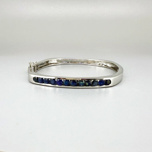 White gold plated silver bangle with natural blue sapphires in a sleek classic design.