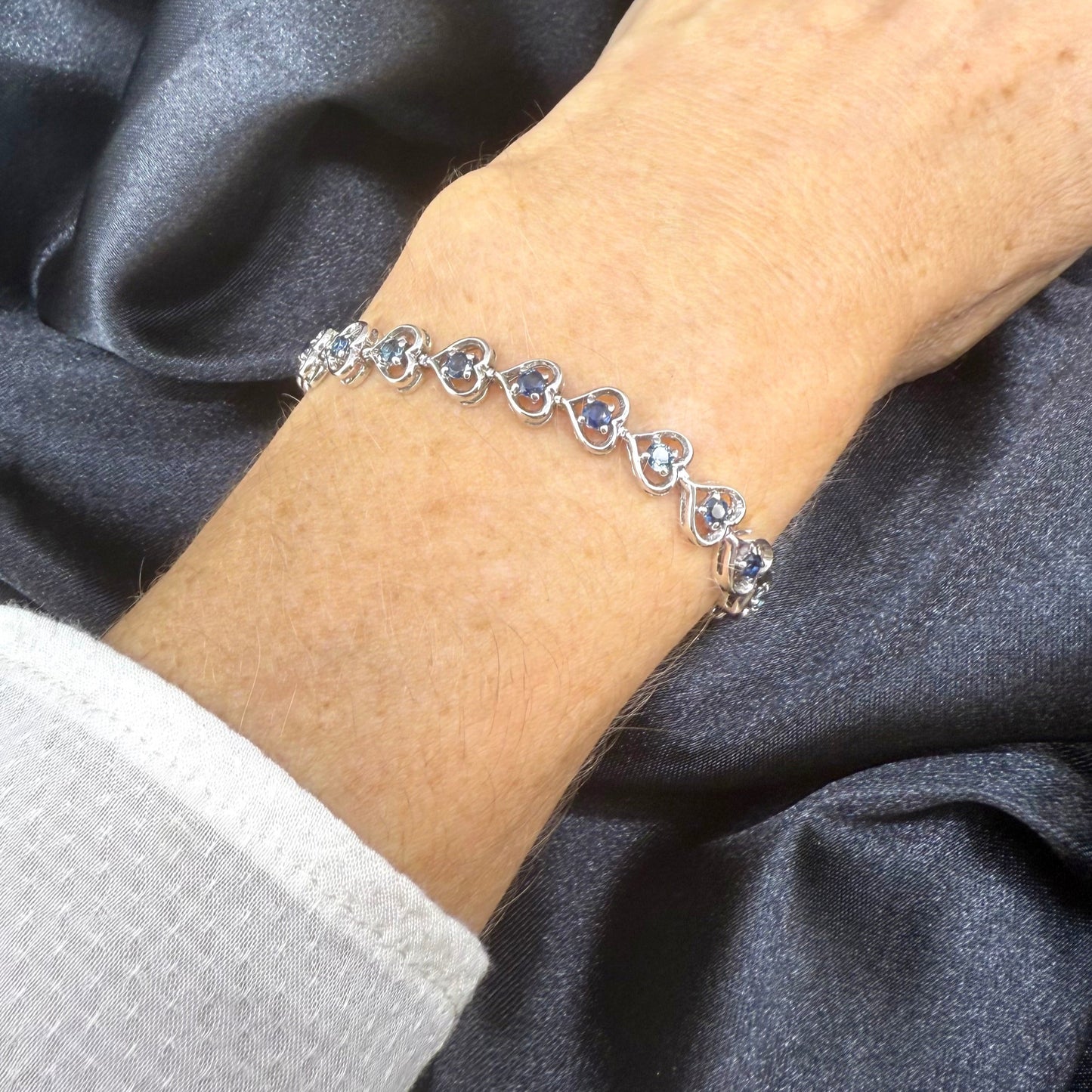 Sapphire bracelet in sterling silver with white gold plating, elegant design on neutral background
