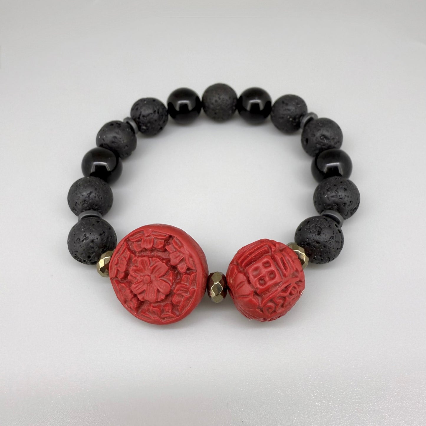 Lava and cinnabar-style beaded bracelet, 18cm, black lava beads with two carved red resin accent beads on elastic stretch band.