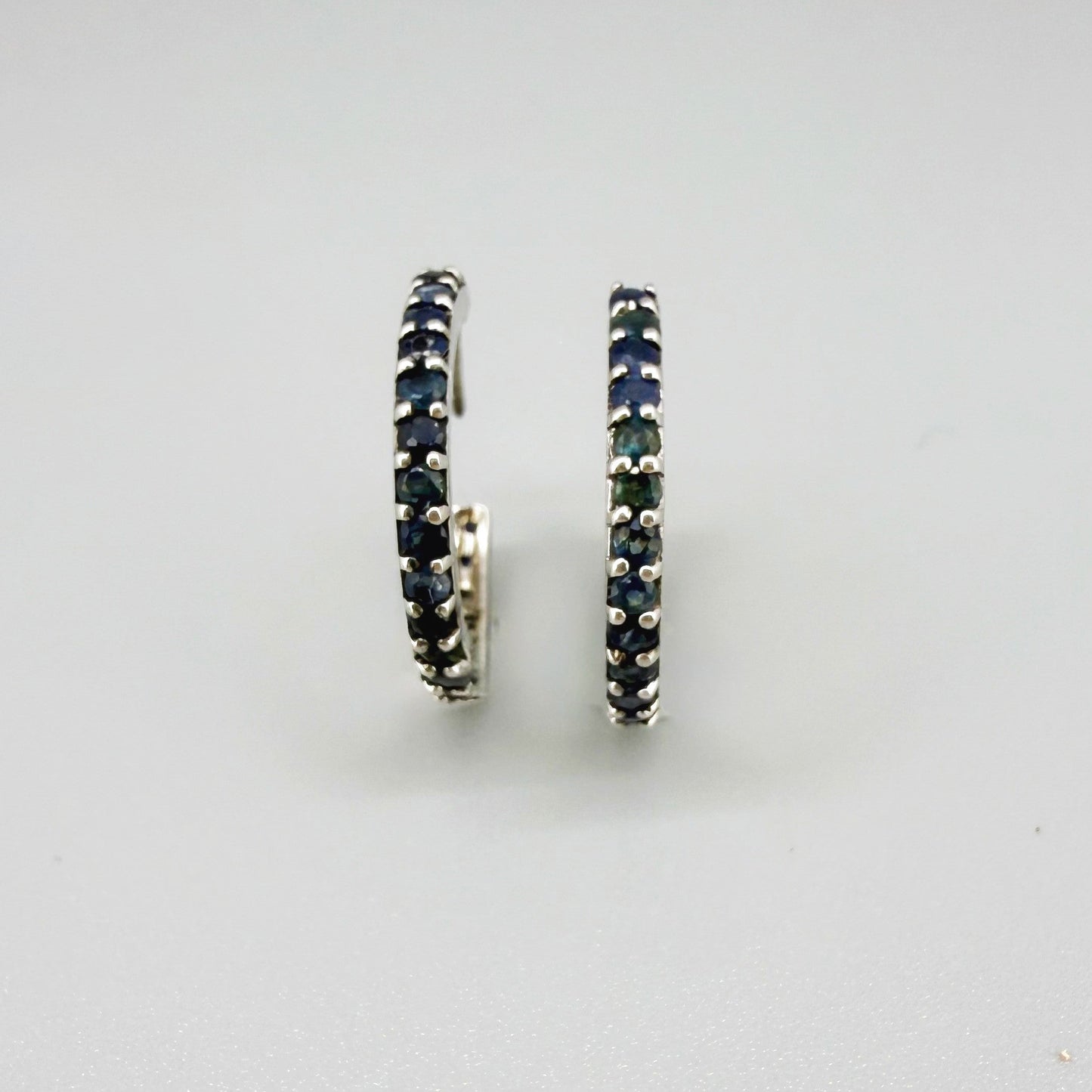 Elegant hoop earrings in white gold plated sterling silver set with natural blue sapphires.