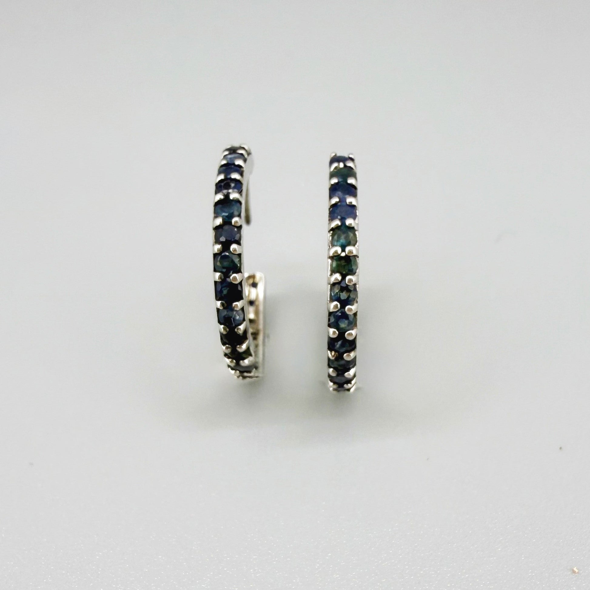 Elegant hoop earrings in white gold plated sterling silver set with natural blue sapphires.