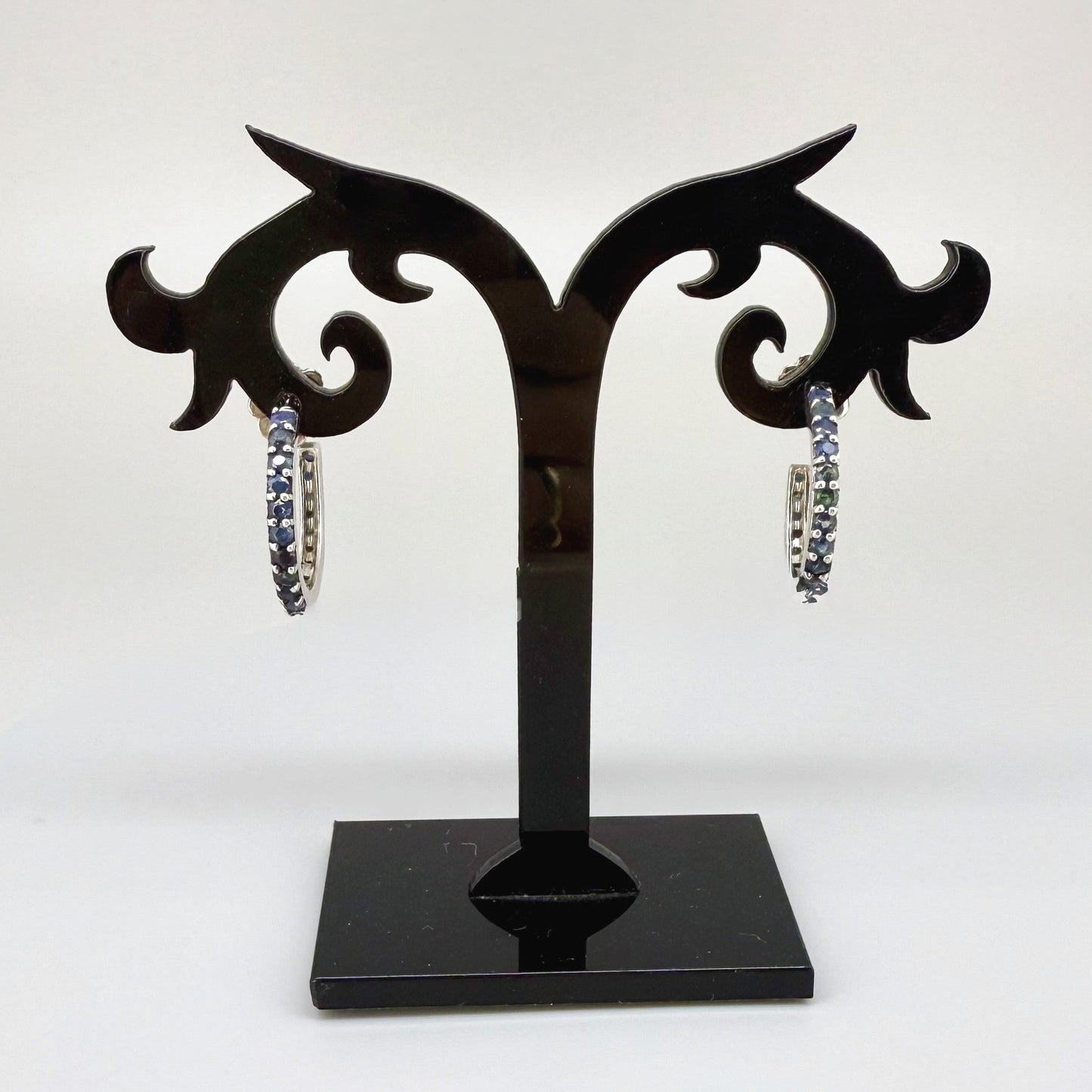 Elegant hoop earrings in white gold plated sterling silver set with natural blue sapphires.