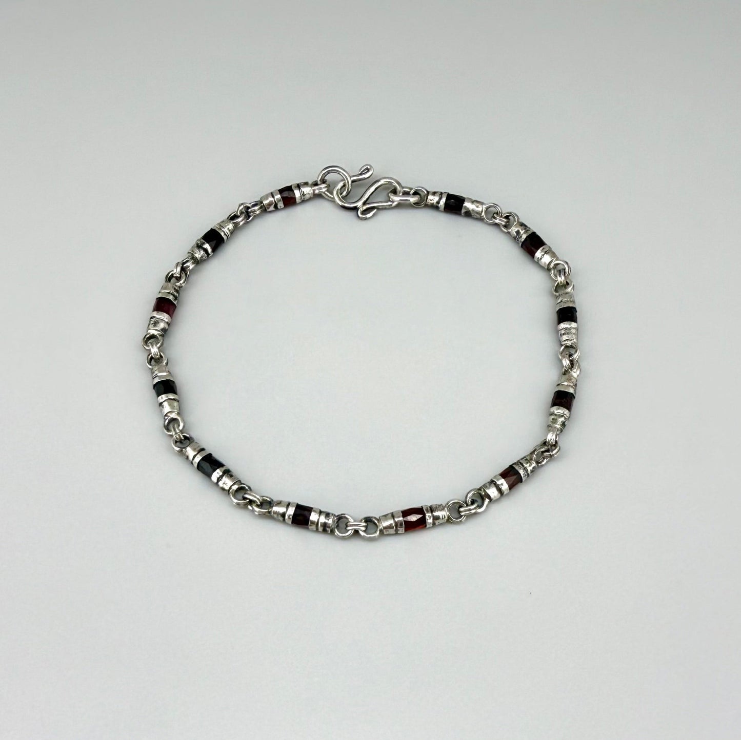 Garnet Pyrope bracelet in sterling silver with white gold plating, elegant design on neutral background
