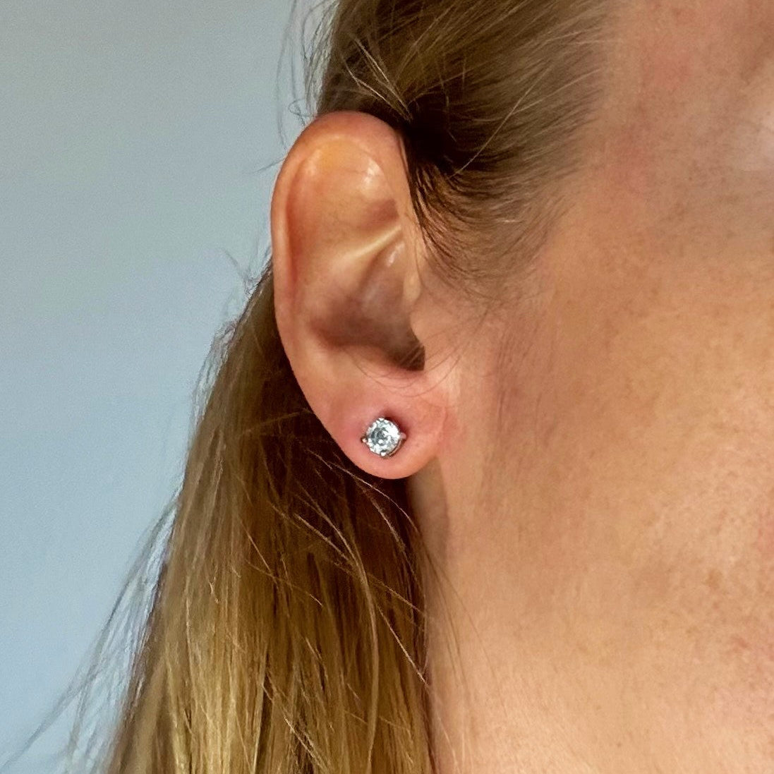 White gold plated sterling silver stud earrings featuring natural blue zircons with high brilliance and clarity.