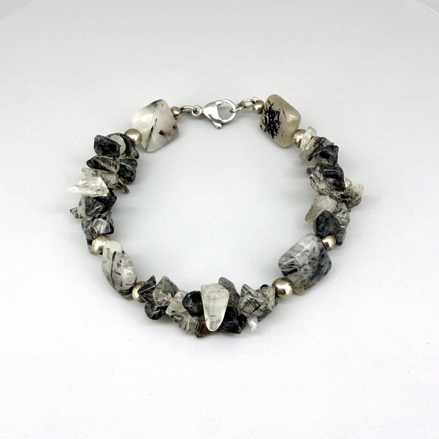 Rutilated quartz bracelet, 19cm, irregular nugget beads in grey, black, and white tones with metal spacers and clasp.