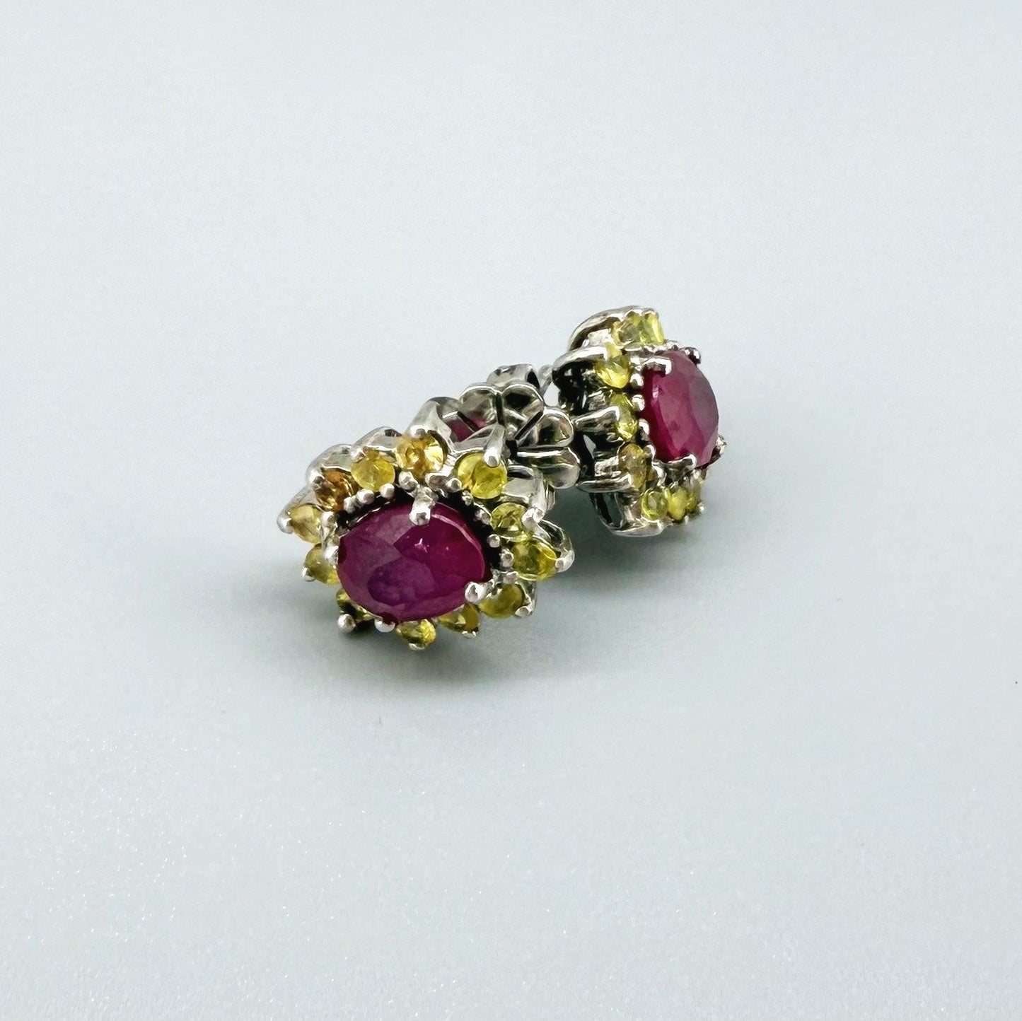 Ruby and yellow sapphire stud earrings in white gold plated sterling silver with butterfly backs.