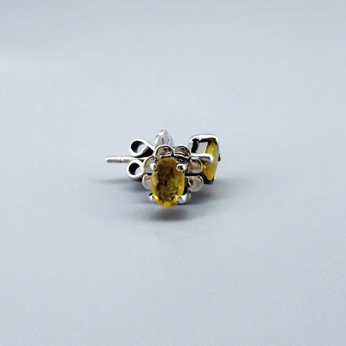 Natural yellow sapphire stud earrings in white gold plated sterling silver with butterfly backs.