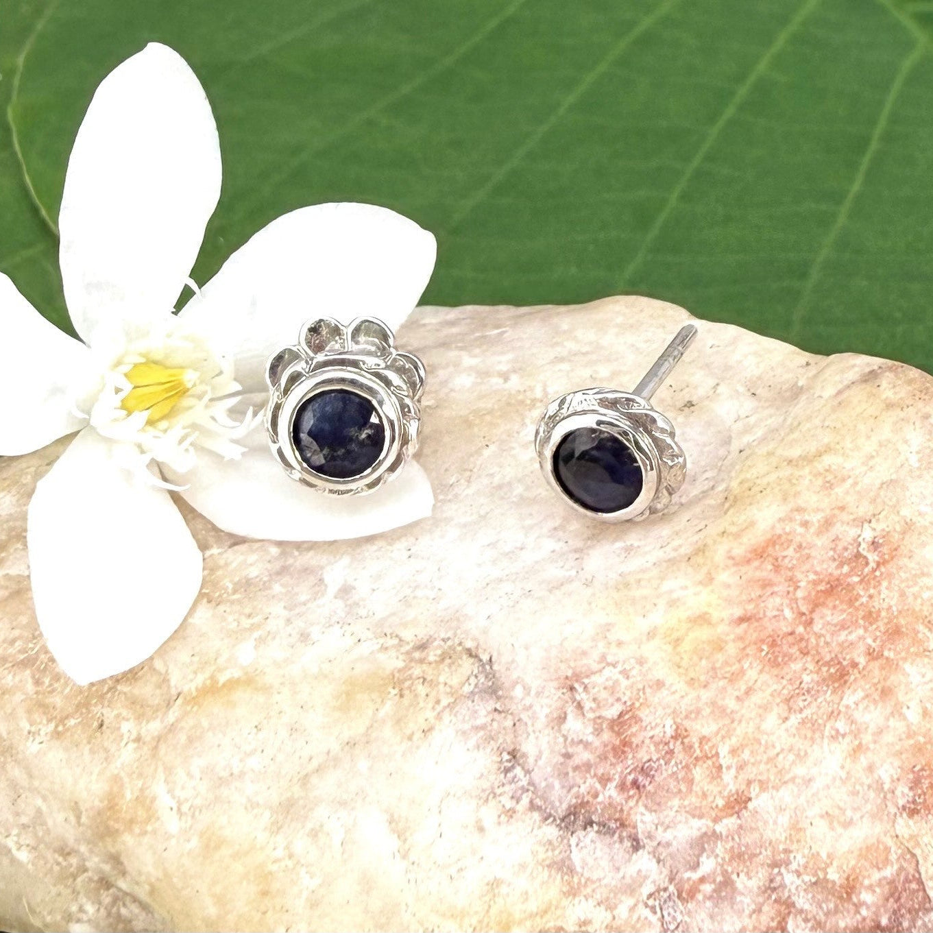 Blue sapphire stud earrings in white gold plated sterling silver with round floral backs.