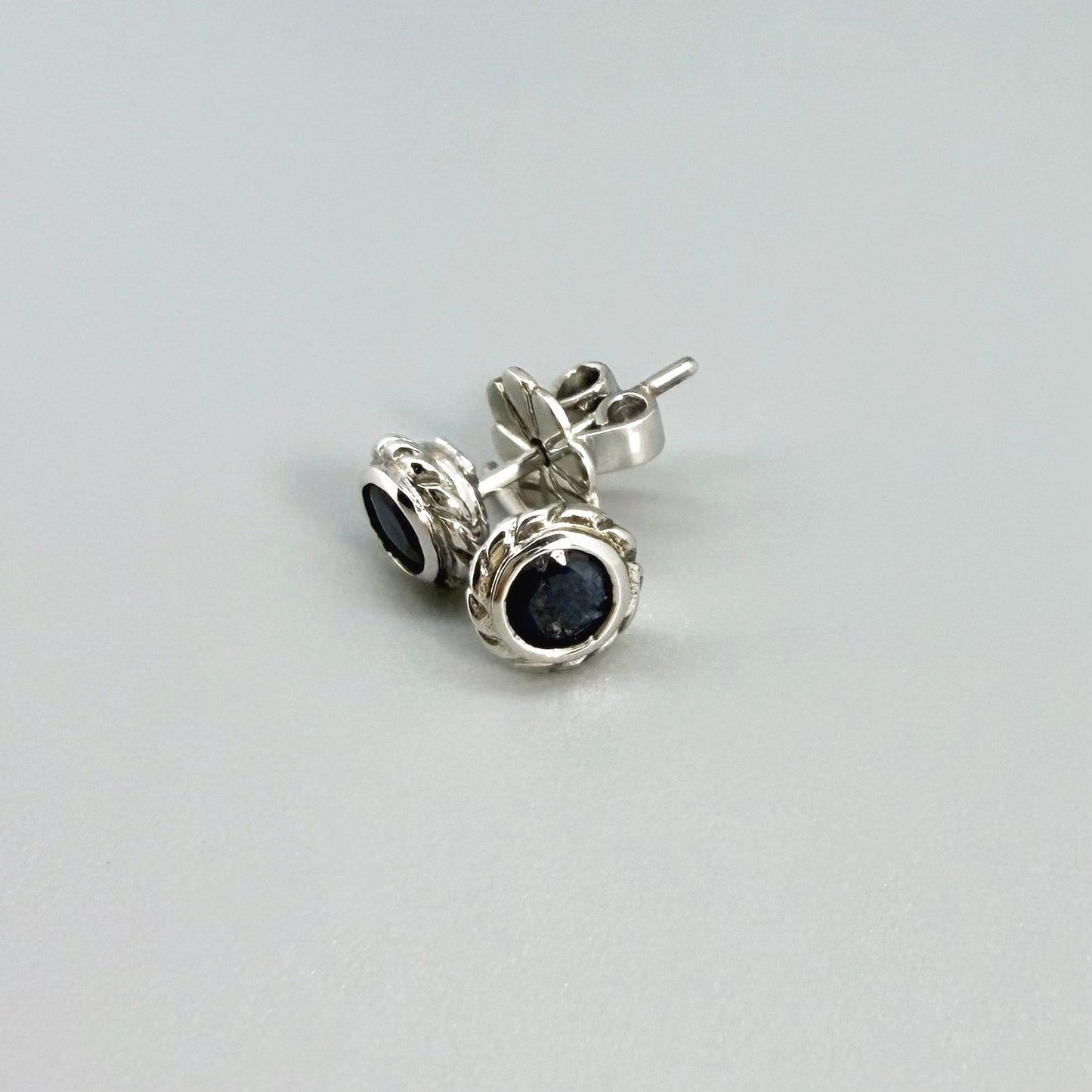 Blue sapphire stud earrings in white gold plated sterling silver with round floral backs.
