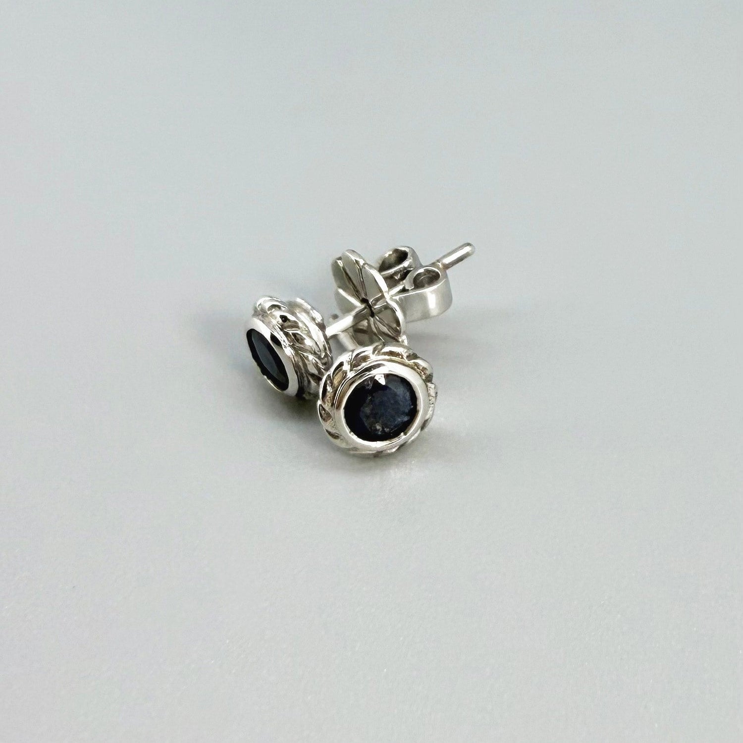 Blue sapphire stud earrings in white gold plated sterling silver with round floral backs.