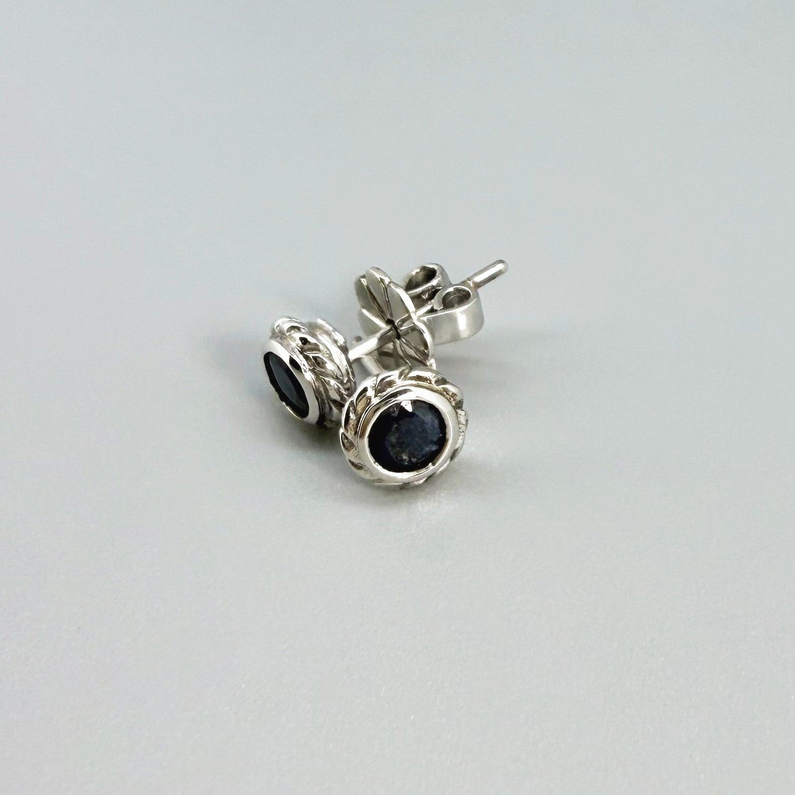 Blue sapphire stud earrings in white gold plated sterling silver with round floral backs.
