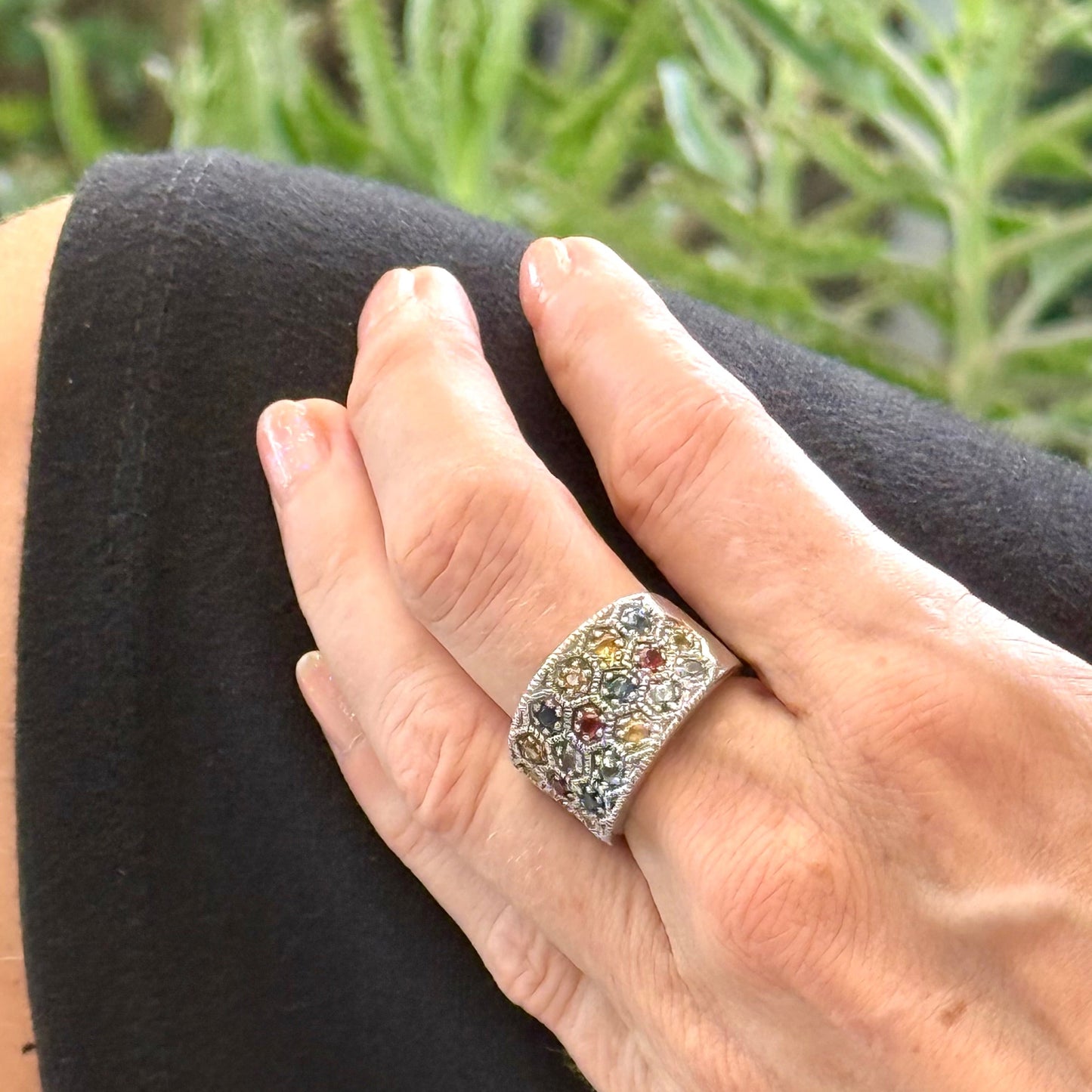 Multicolor sapphire band ring in white gold plated sterling silver, featuring faceted blue, yellow, pink, green, and orange gemstones, elegant wide design.