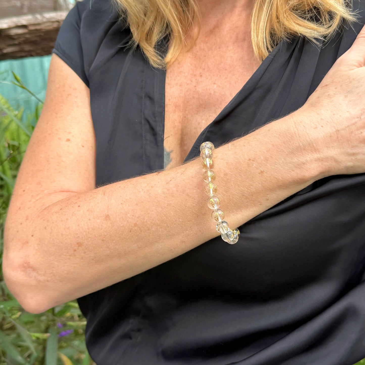Clear quartz mala bracelet with 21 engraved beads featuring golden Om Mani Padme Hum mantra on elastic cord