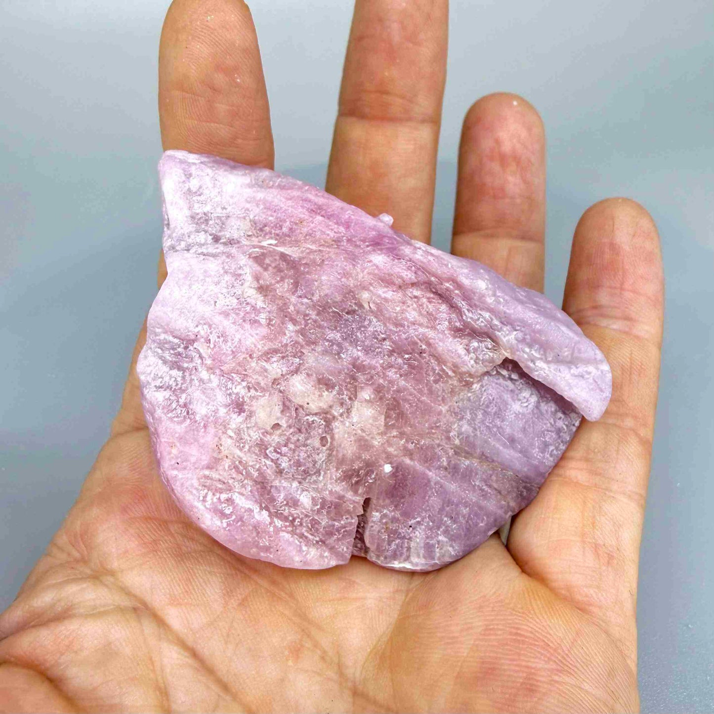 Natural ruby rough stone in soft pink to pale rose tones, uncut corundum specimen photographed on neutral background.