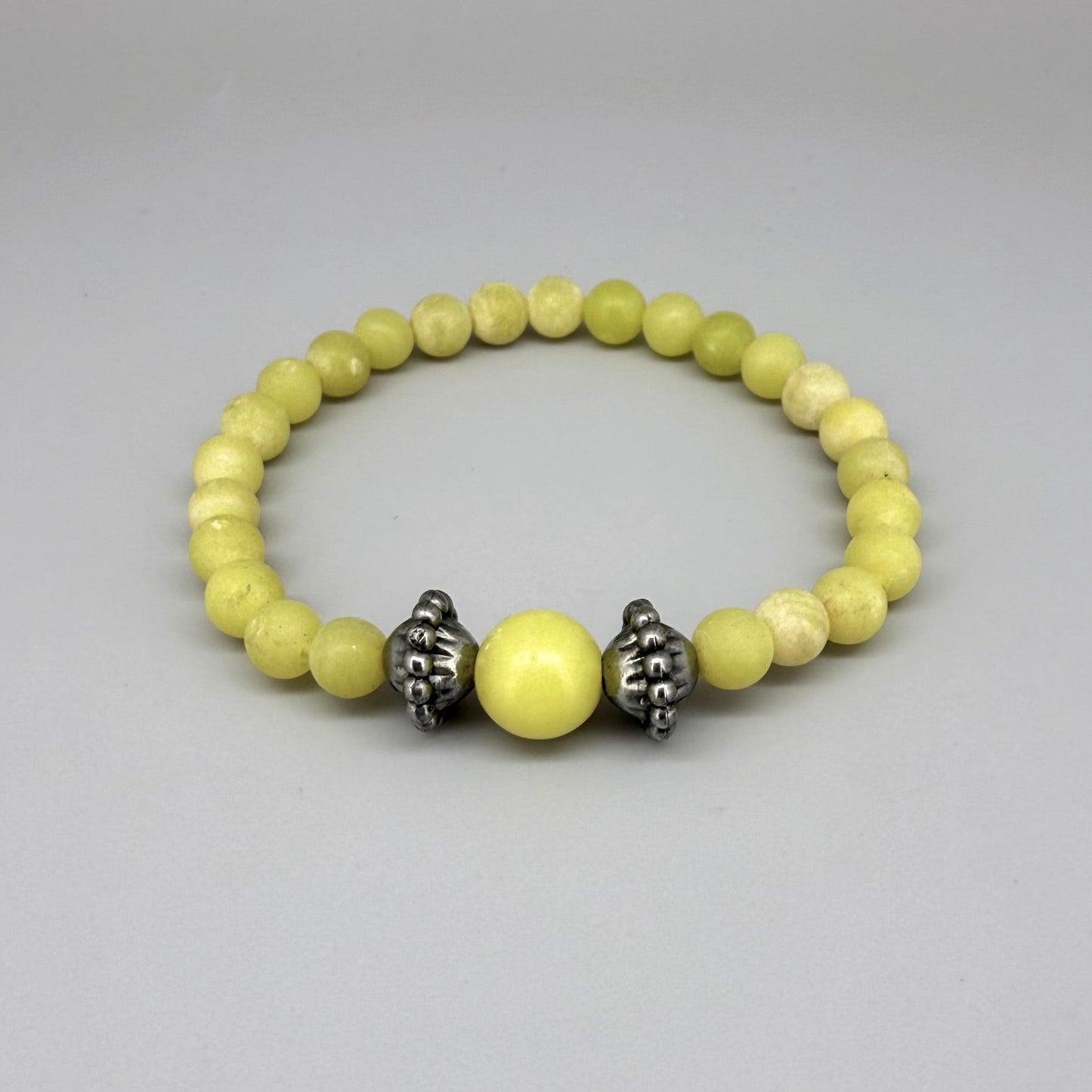 Yellow jasper beaded bracelet, 18cm, vibrant gemstone beads with larger focal bead framed by carved metal accents on elastic stretch band.