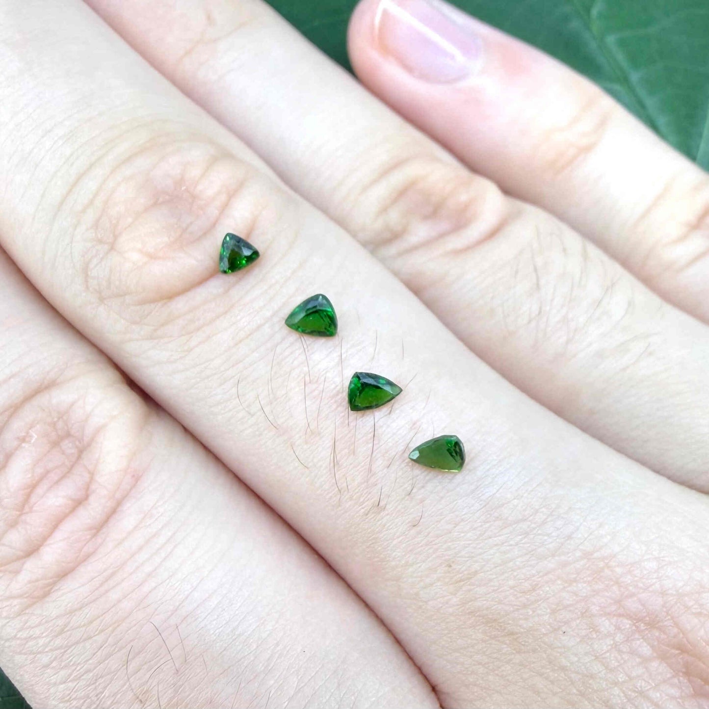 Small lot of four natural vibrant-green diopside stones, trillion cut, total 0.54 ct.