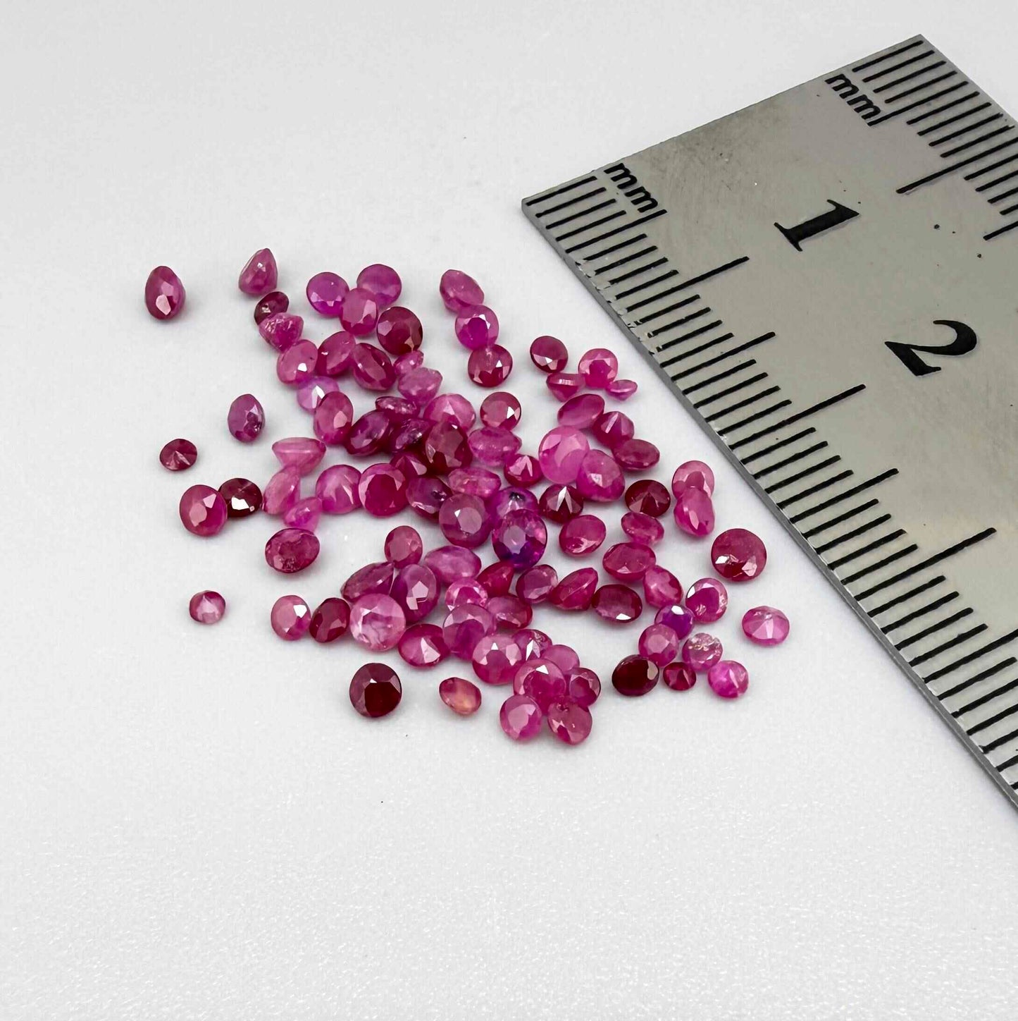 Ruby parcel with mixed pinkish red to reddish pink tones in small faceted cuts, showing natural inclusions and lively brilliance.