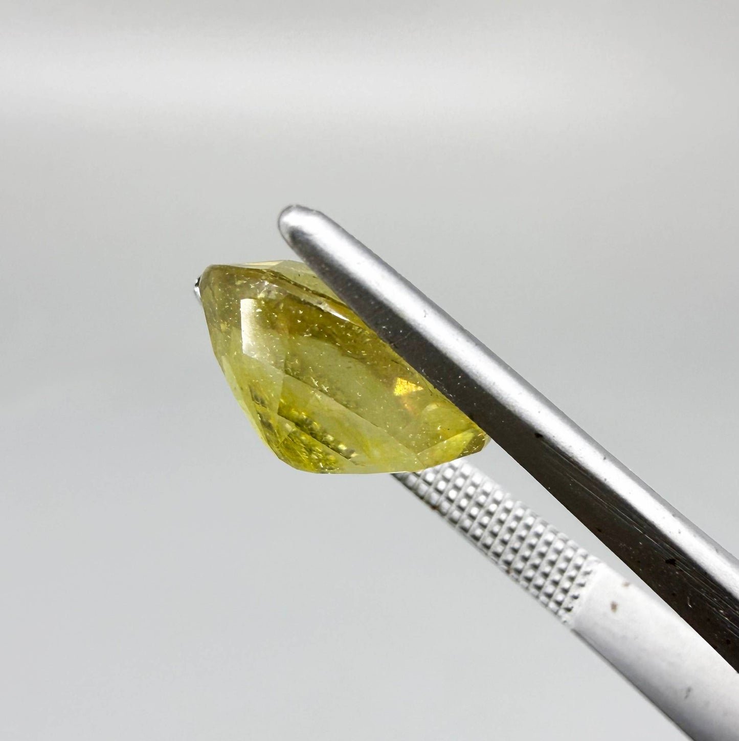 Oval yellow sapphire from Africa, 5.42ct, with vivid golden-yellow color, visible natural inclusions and a transparent to slightly silky appearance.
