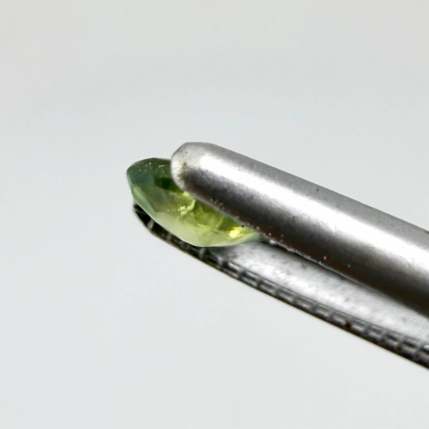 Oval light green sapphire from Thailand, 0.33ct, unheated, with soft green color, visible banding and natural inclusions and a transparent to slightly silky appearance.