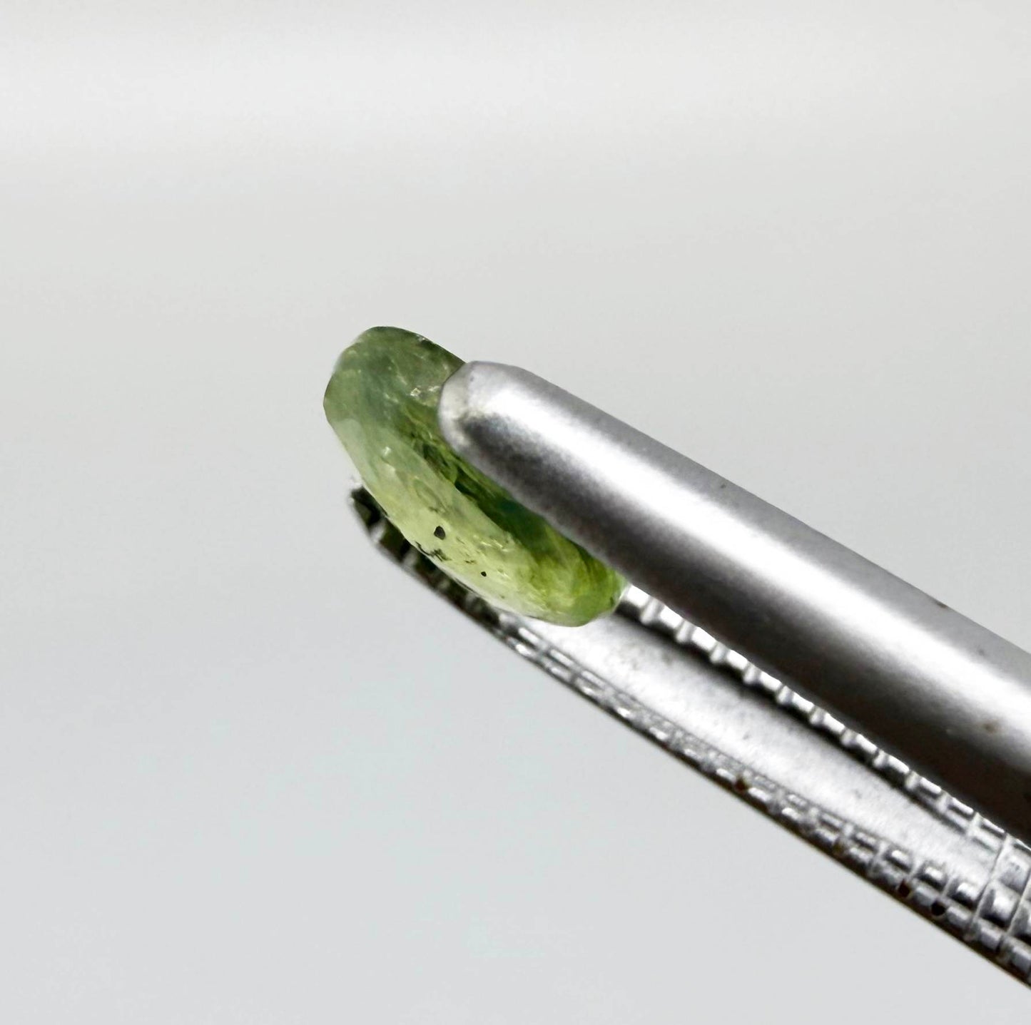 Oval light green sapphire from Thailand, 0.42ct, unheated, with soft pistachio-green color, visible natural inclusions and a transparent to slightly silky appearance.