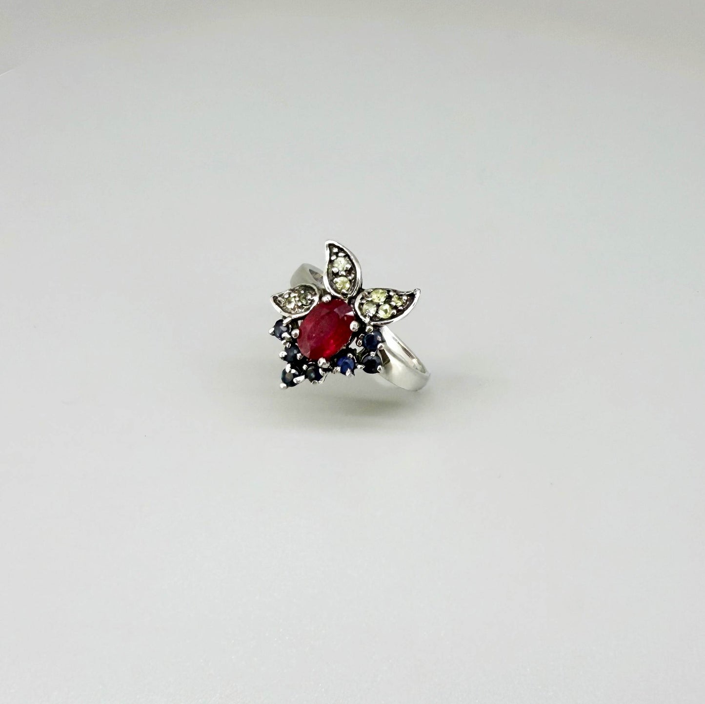 Sterling silver ring featuring a natural ruby at the center, accented by sapphires and peridot in a colorful gemstone cluster design.