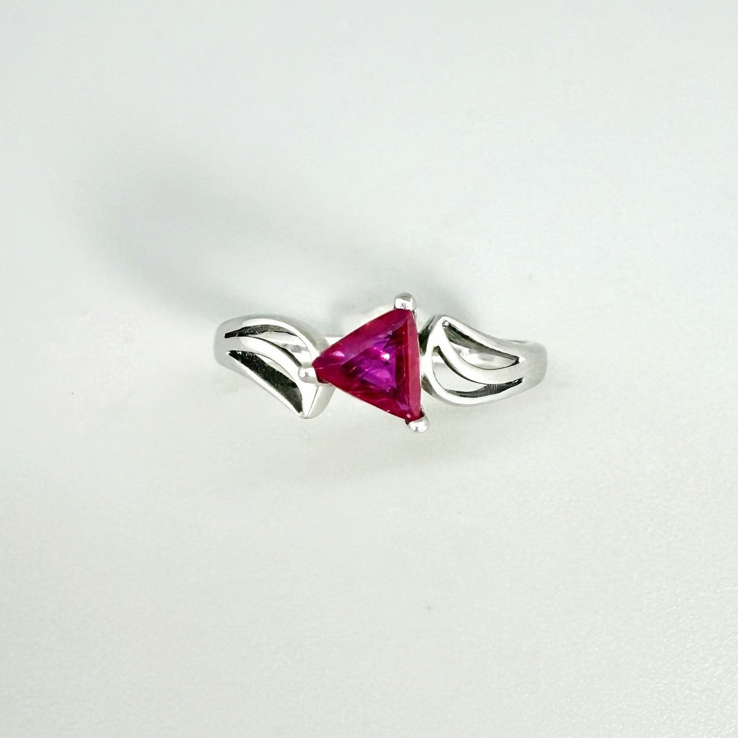 Ruby triangle-cut ring in white gold plated sterling silver, featuring a vivid red natural gemstone in a modern geometric solitaire design.