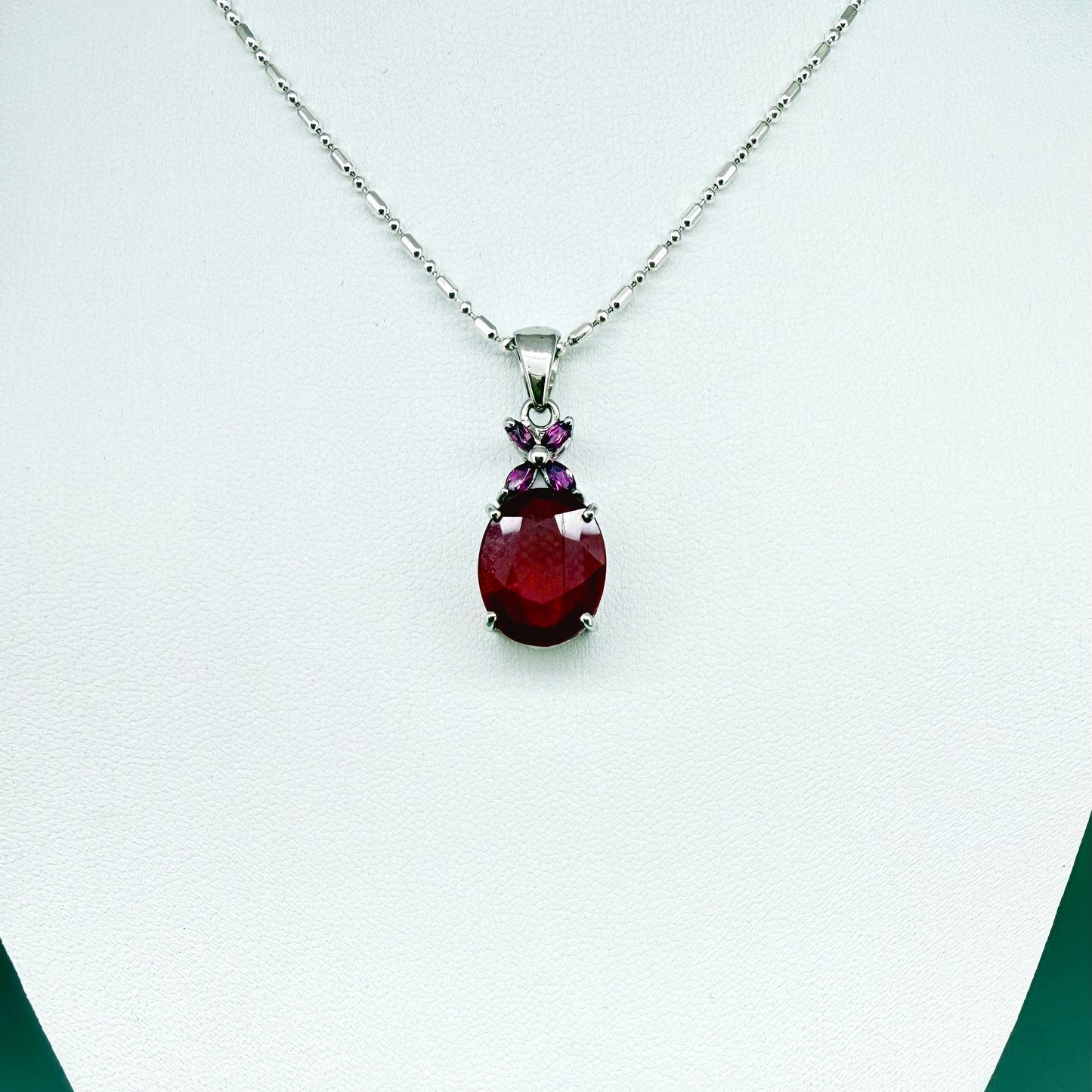 White gold plated silver pendant featuring a 7.87 ct ruby and 0.33 ct rhodolite garnets; elegant red and pink gemstone design.