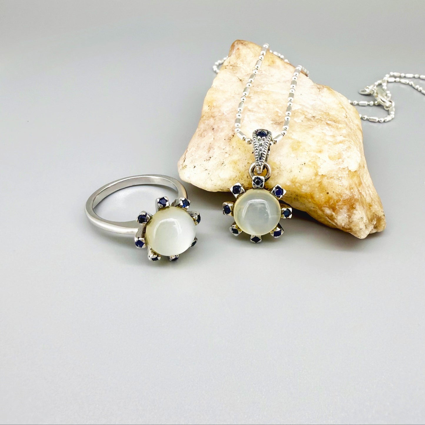 Handcrafted pendant featuring 3.75 ct natural moonstone and 0.35 ct blue sapphires set in white-gold-plated sterling silver.