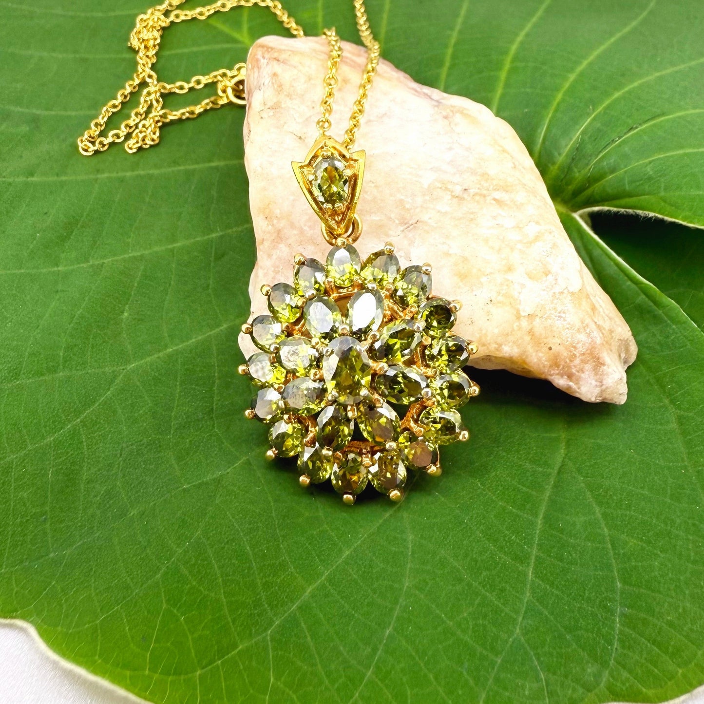 Gold-plated sterling silver pendant with natural green sapphires in a floral-inspired design.