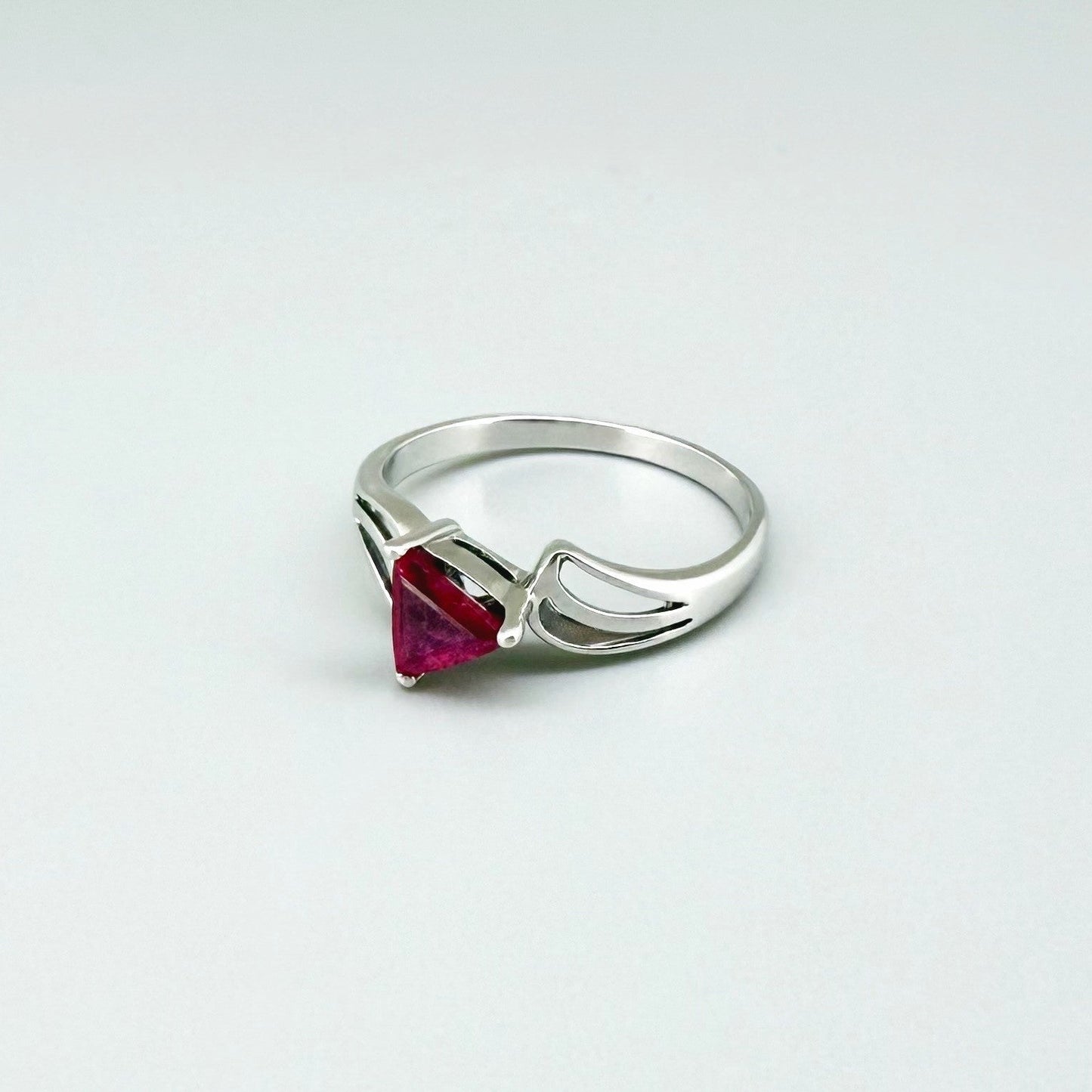 Ruby triangle-cut ring in white gold plated sterling silver, featuring a vivid red natural gemstone in a modern geometric solitaire design.
