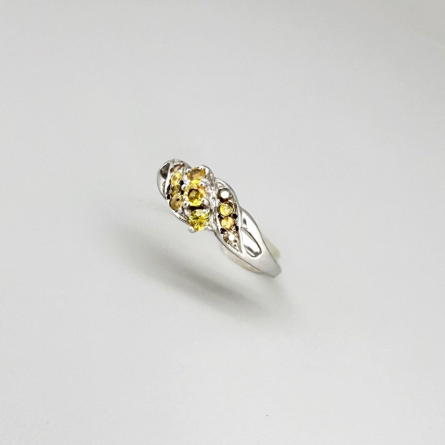 White gold plated sterling silver ring featuring two marquise-cut yellow sapphires in an elegant bypass setting.
