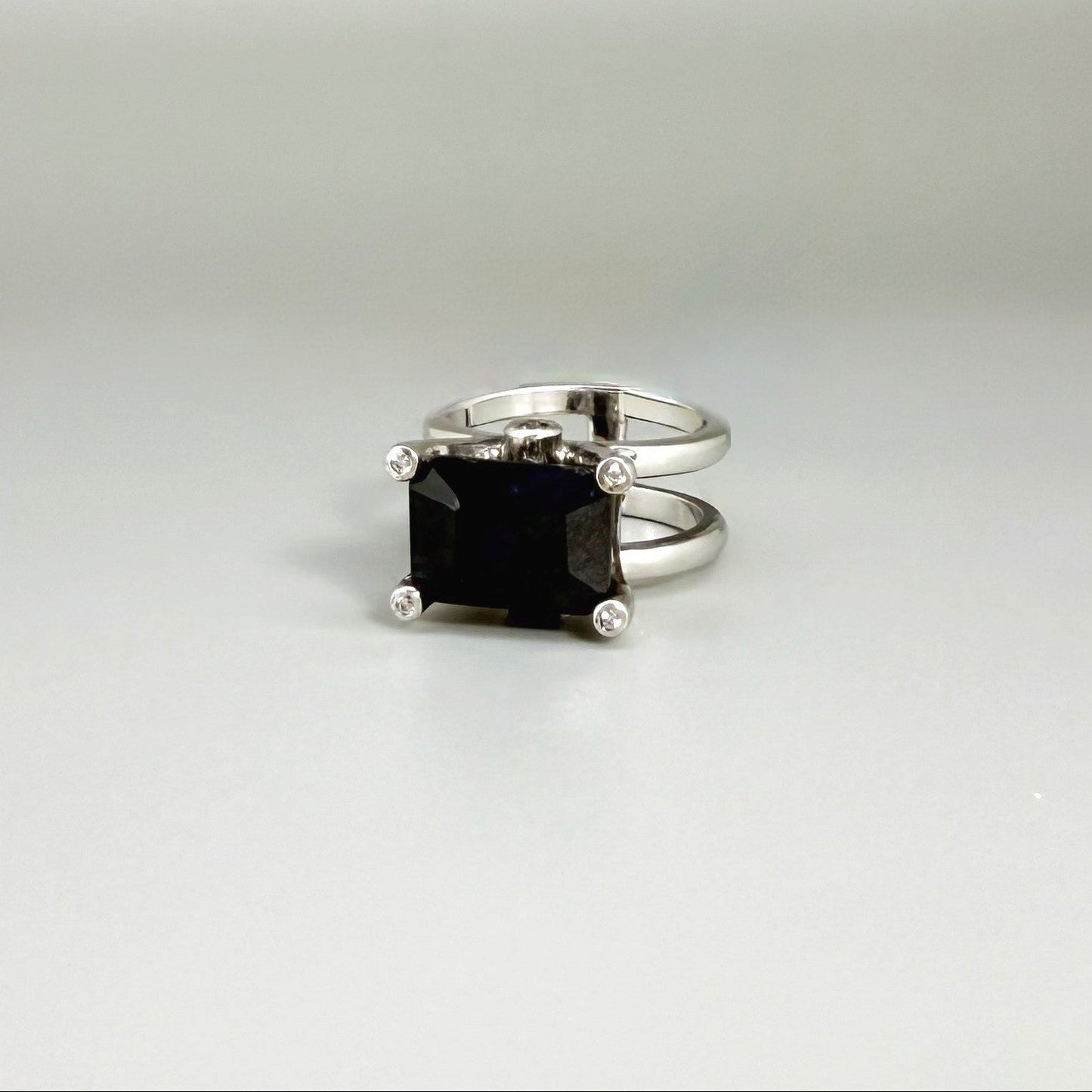 Emerald-cut sapphire ring in white gold plated sterling silver, featuring a natural deep blue gemstone in a bold and elegant solitaire design.
