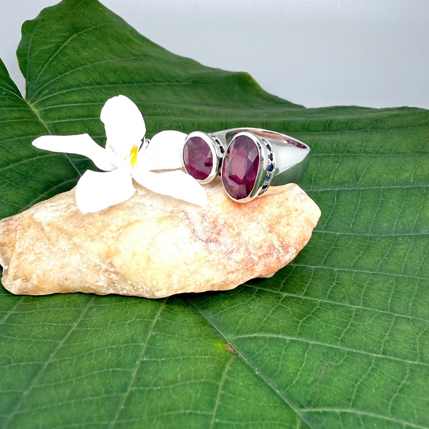 Ruby and sapphire bypass ring in white gold plated sterling silver, featuring two natural red rubies framed by blue sapphires in an open design, elegant and bold style.