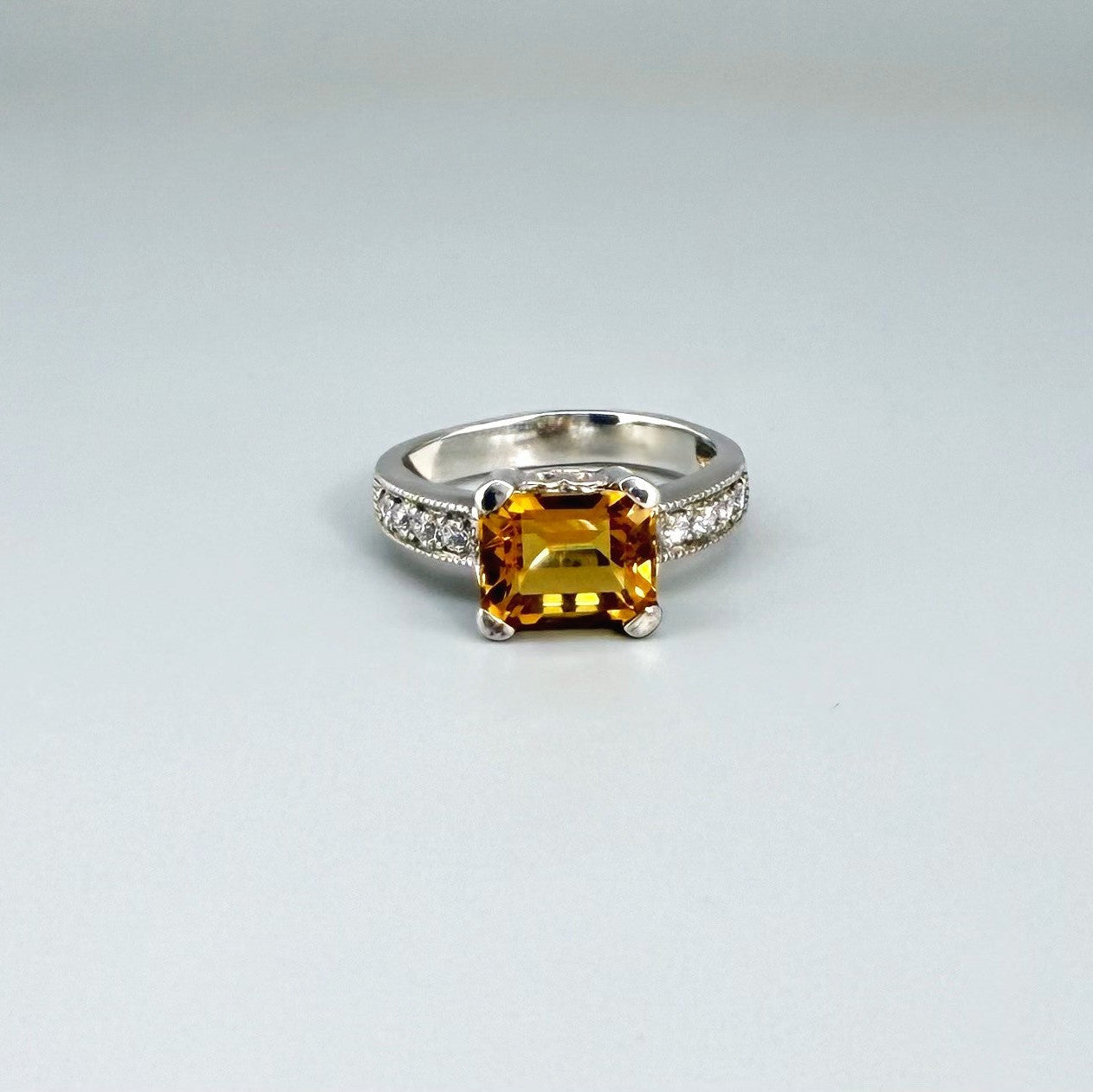 Citrine and CZ ring in white gold plated sterling silver, featuring a faceted golden gemstone framed by clear cubic zirconia, elegant and radiant design.